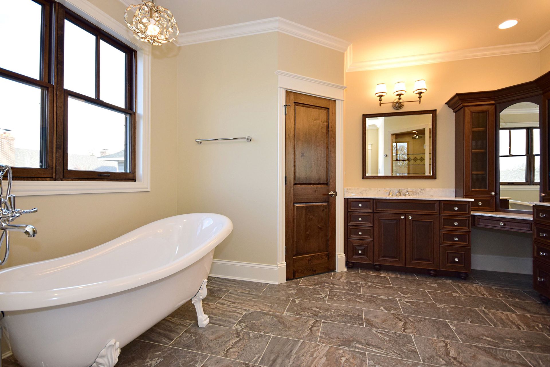 A bathroom with a claw foot tub , sink , mirror and window.