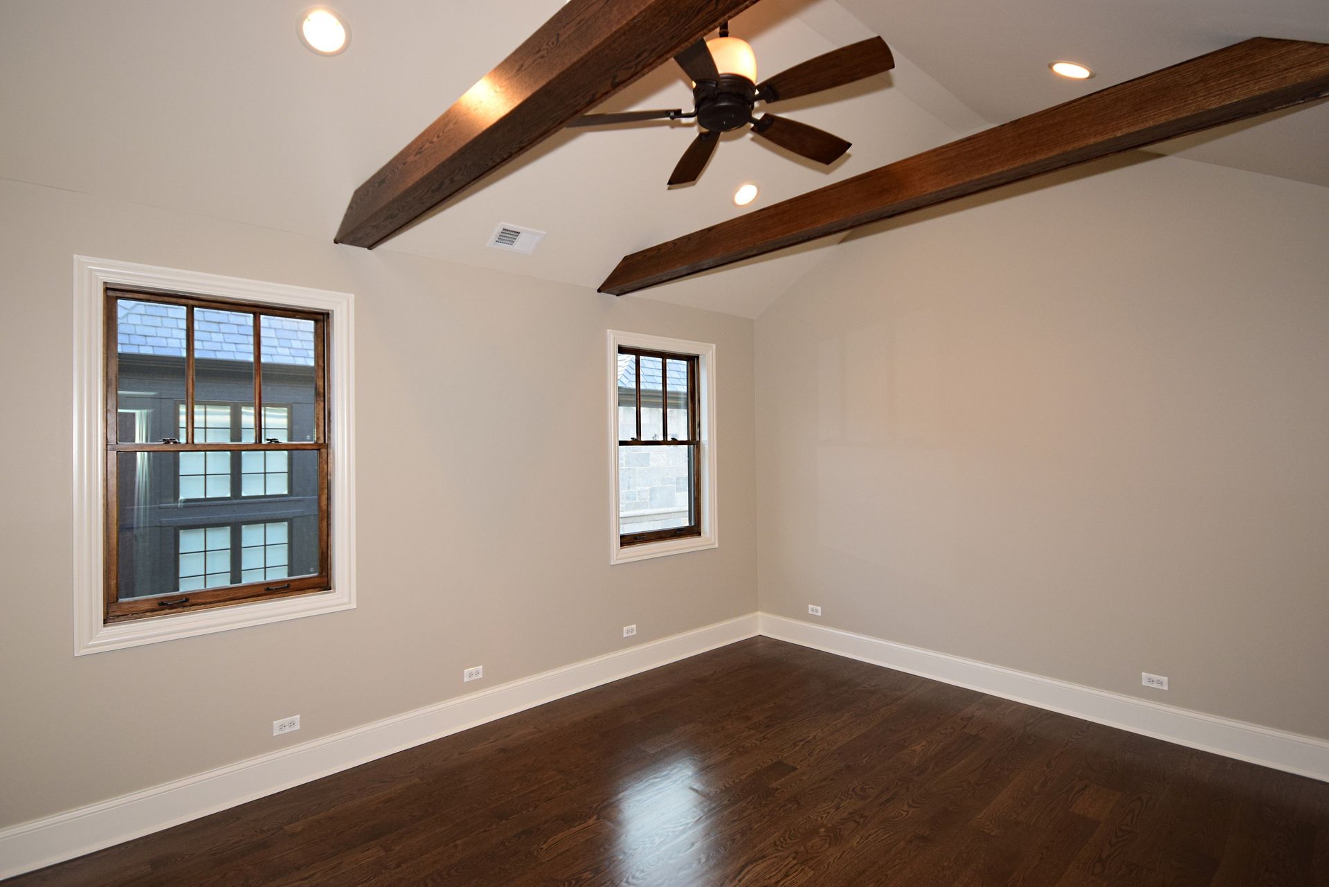 An empty room with a ceiling fan and two windows