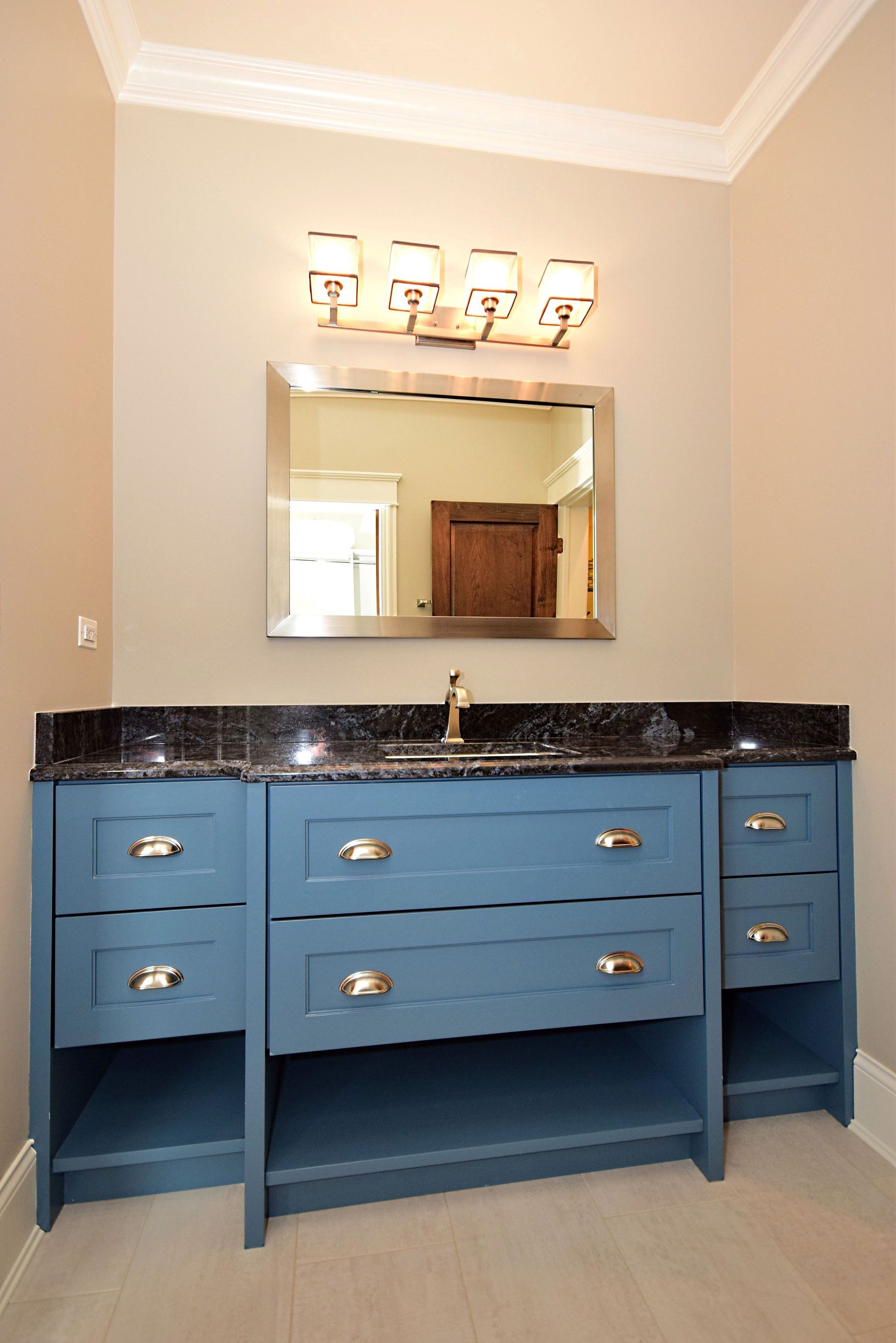 A bathroom with a blue vanity and a mirror