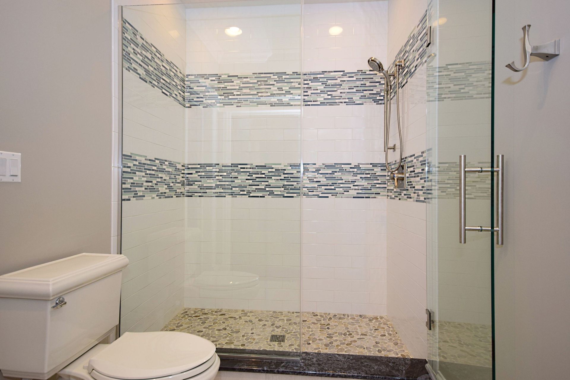 A bathroom with a toilet , shower and glass door.