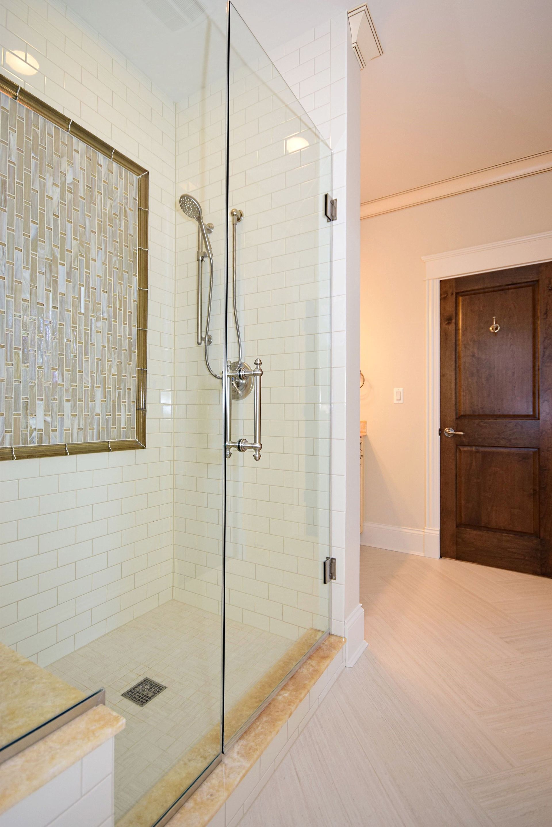 A bathroom with a walk in shower with a glass door