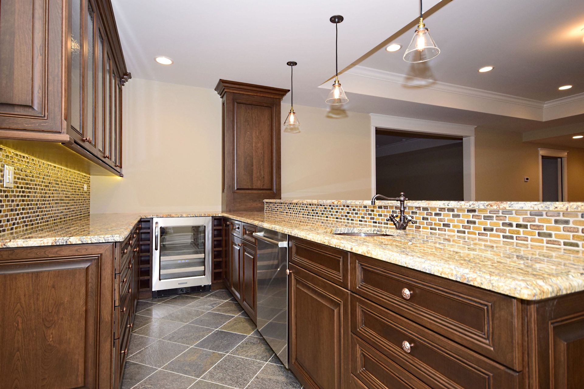 A kitchen with wooden cabinets , granite counter tops , stainless steel appliances and a wine cooler.