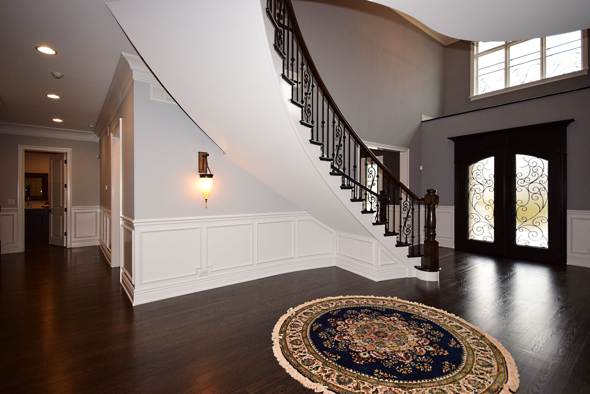 An empty hallway with a staircase and a rug in the middle