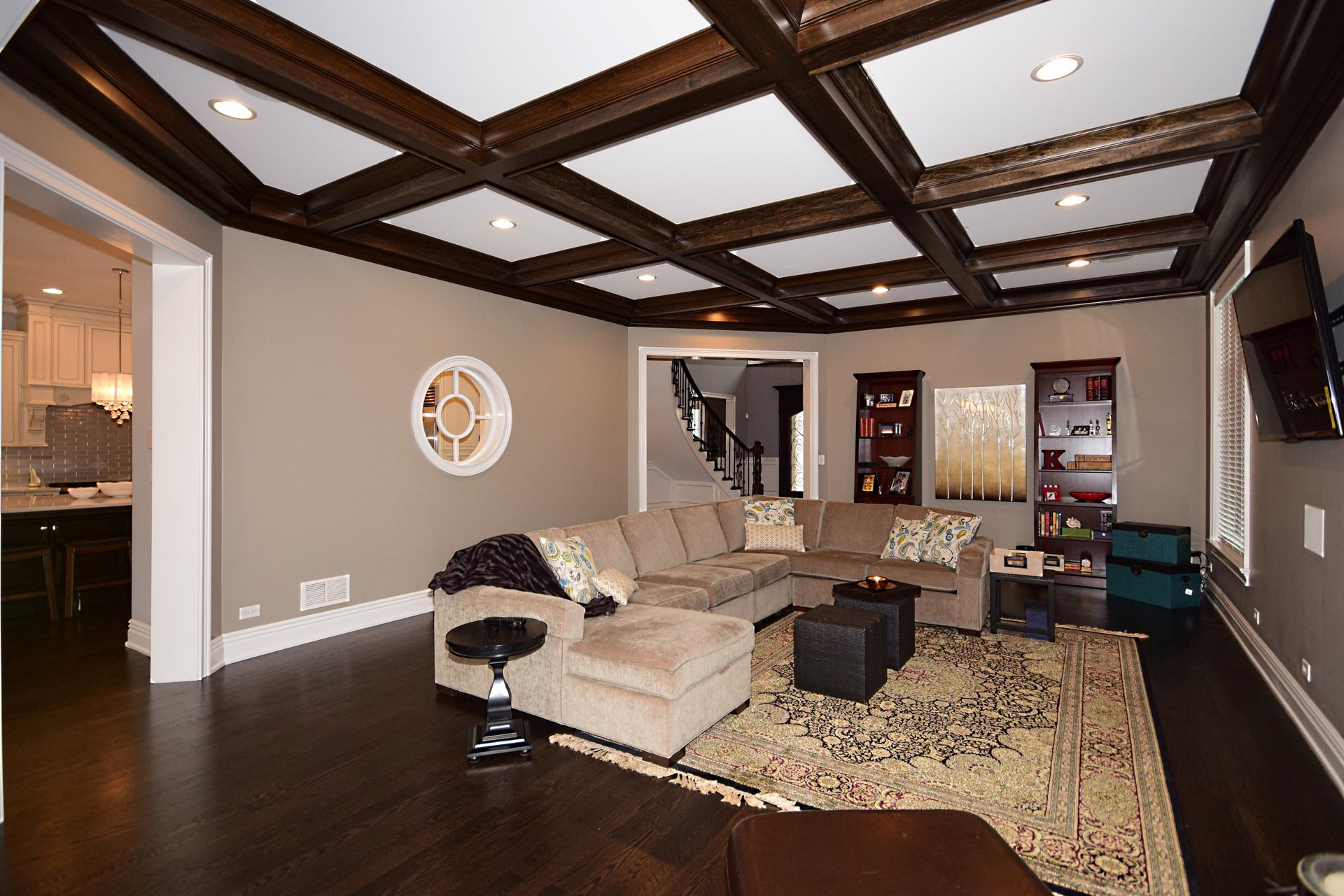 A living room with a coffered ceiling and a sectional couch