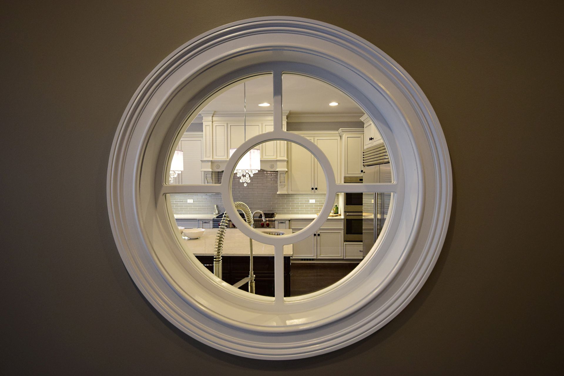 A round mirror on a wall with a kitchen in the background