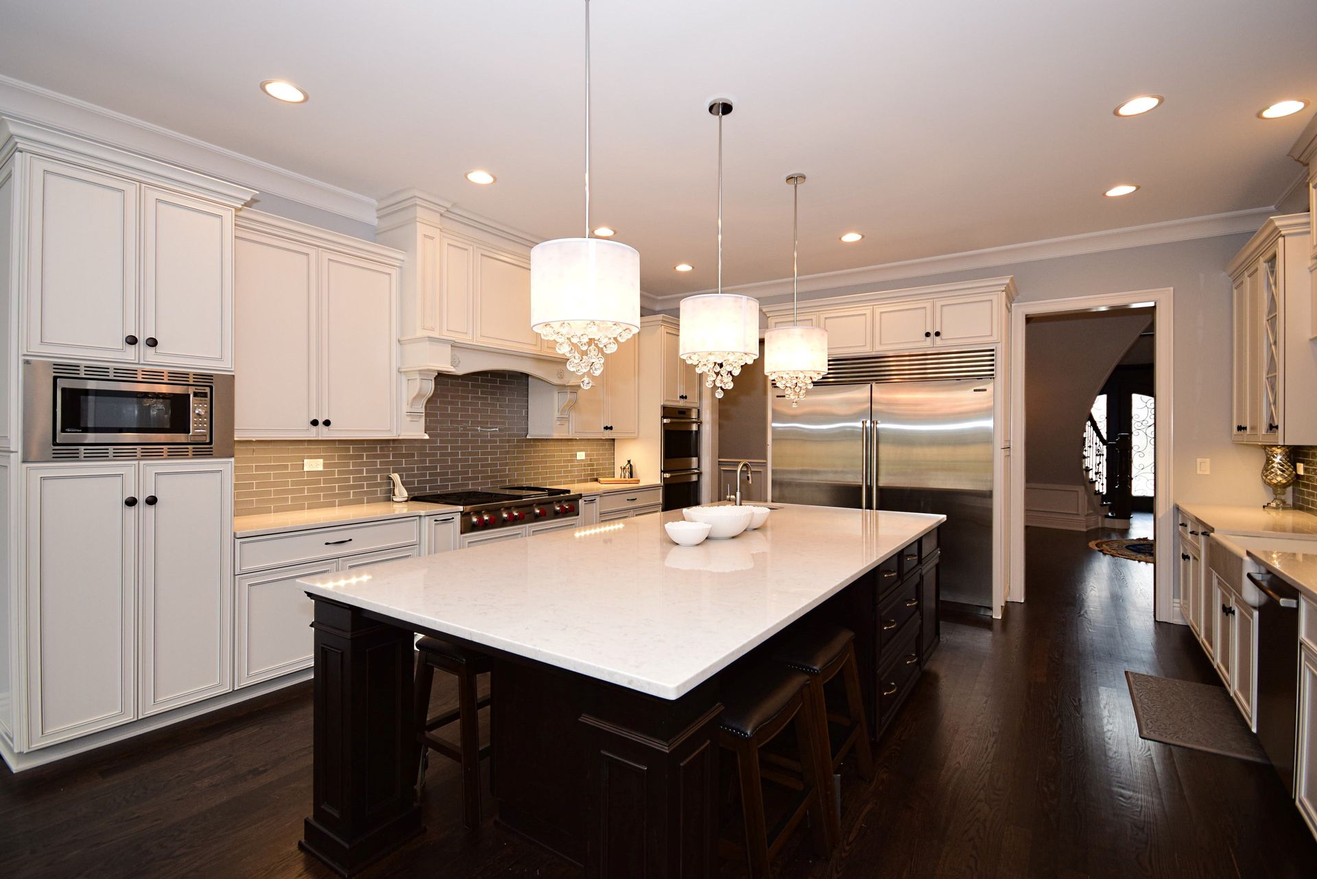 A kitchen with white cabinets and a large island in the middle