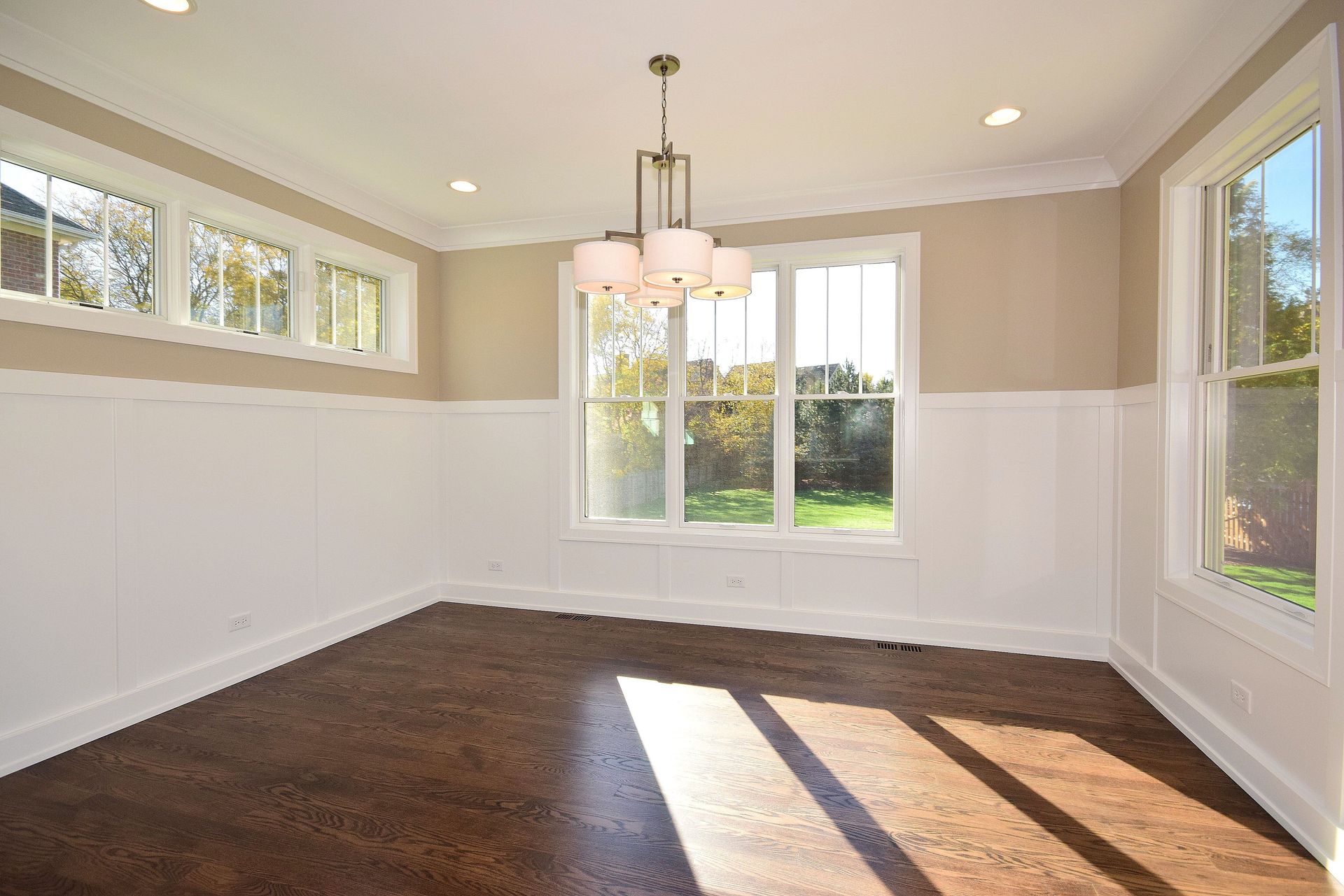 An empty dining room with a chandelier and lots of windows.