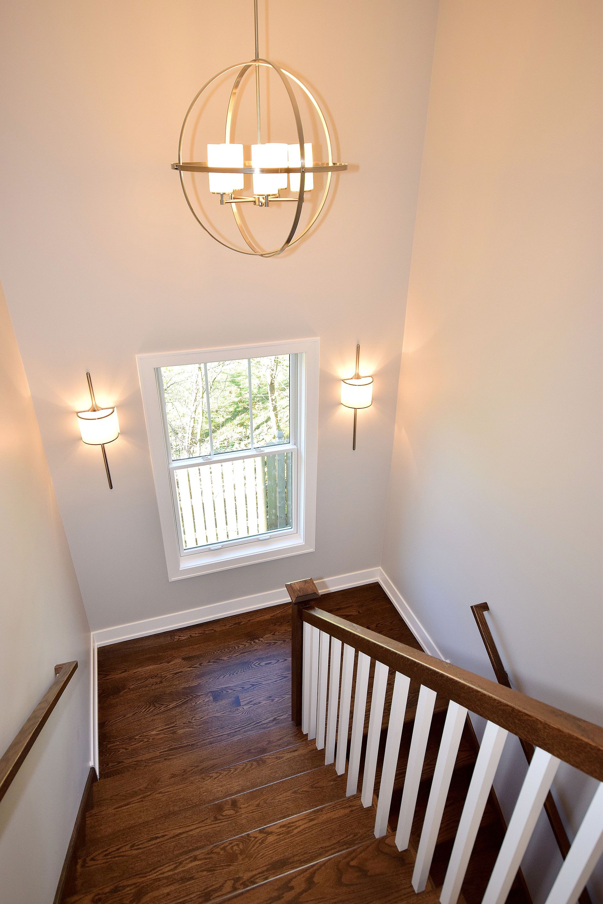A staircase with a window and a chandelier hanging from the ceiling.
