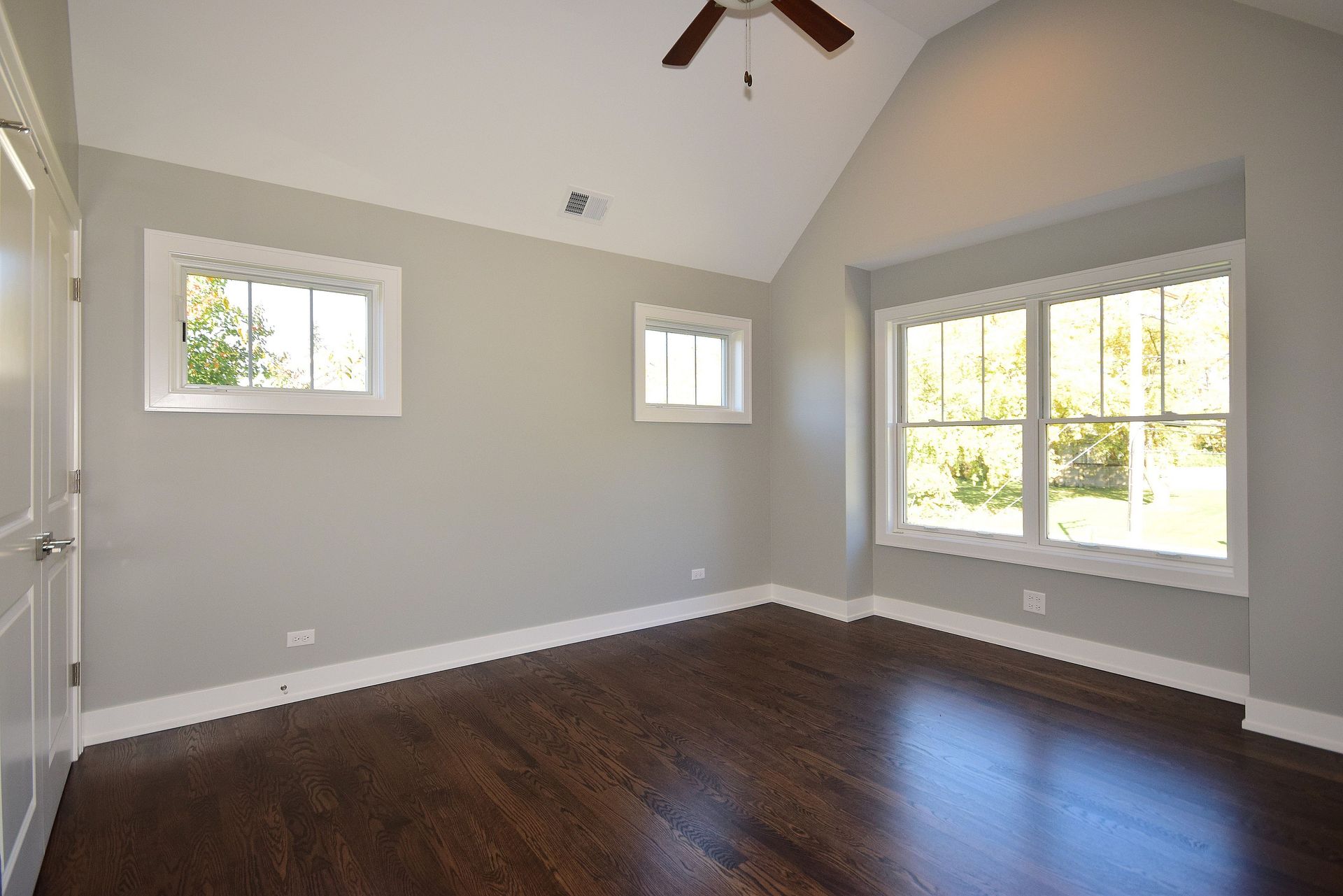 An empty room with a vaulted ceiling and a ceiling fan.