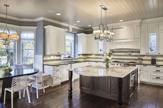 A kitchen with white cabinets and a large island in the middle