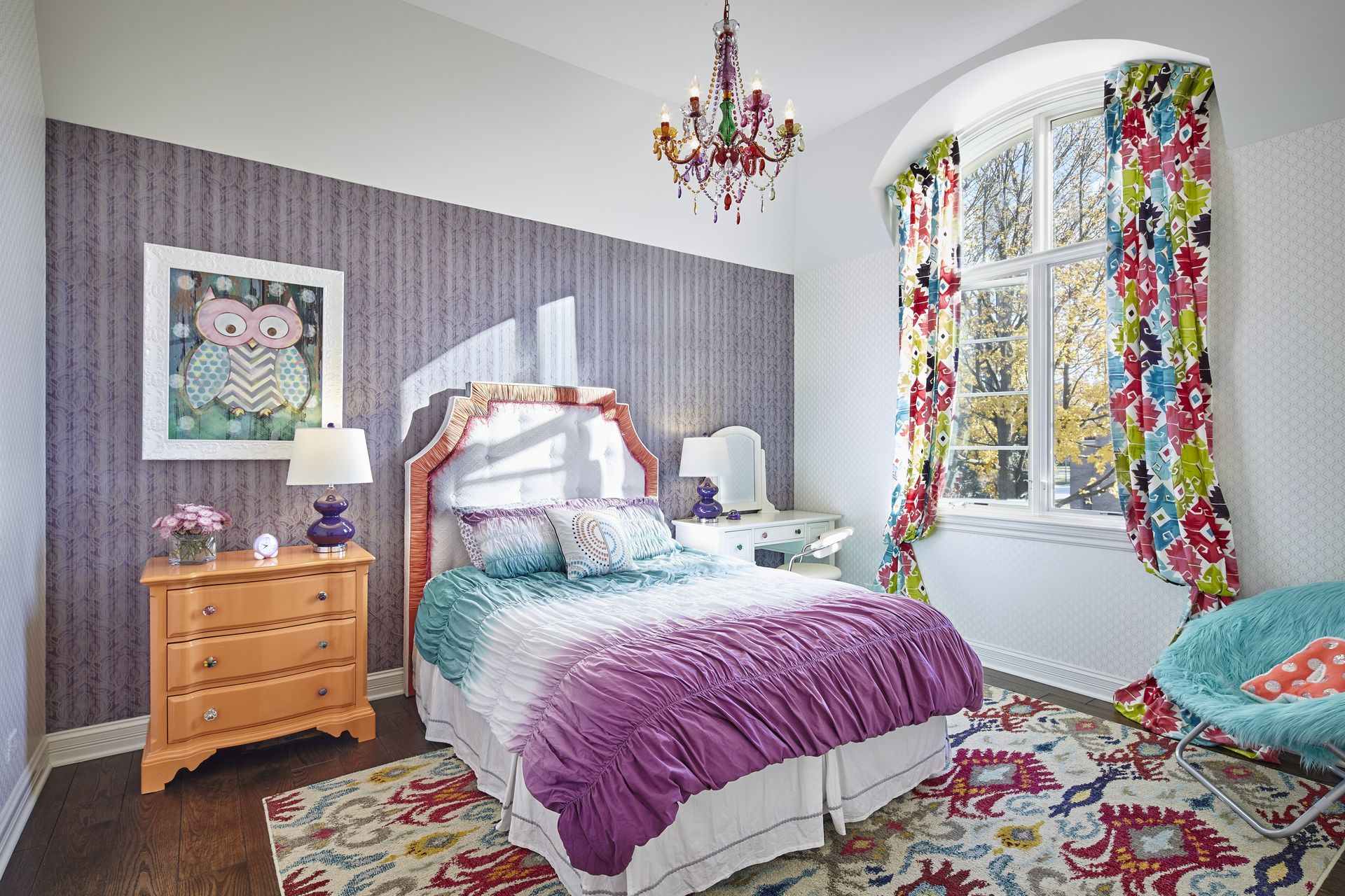 A bedroom with a bed , dresser , chair and chandelier.