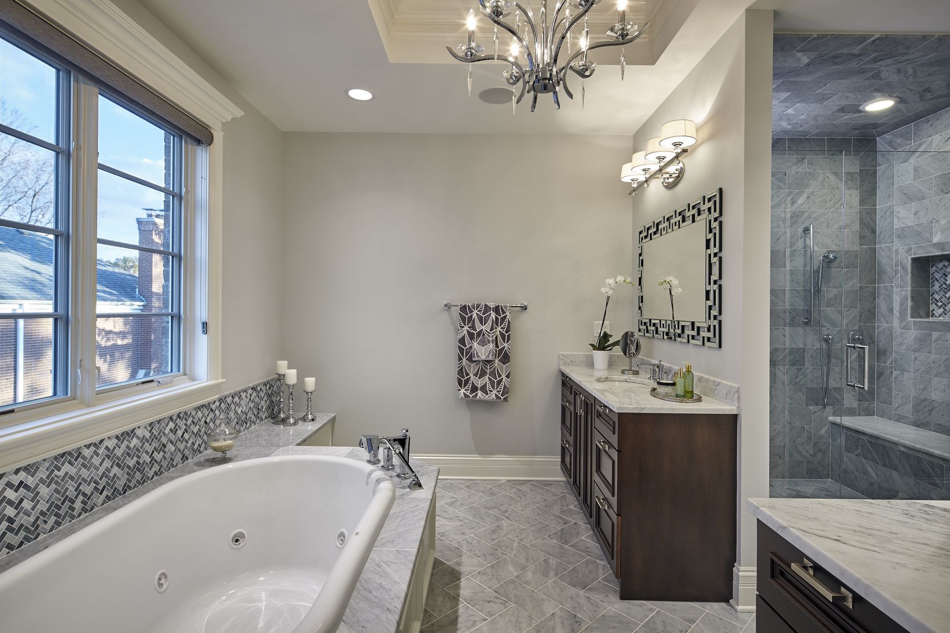A bathroom with a bathtub , sink , mirror and chandelier.