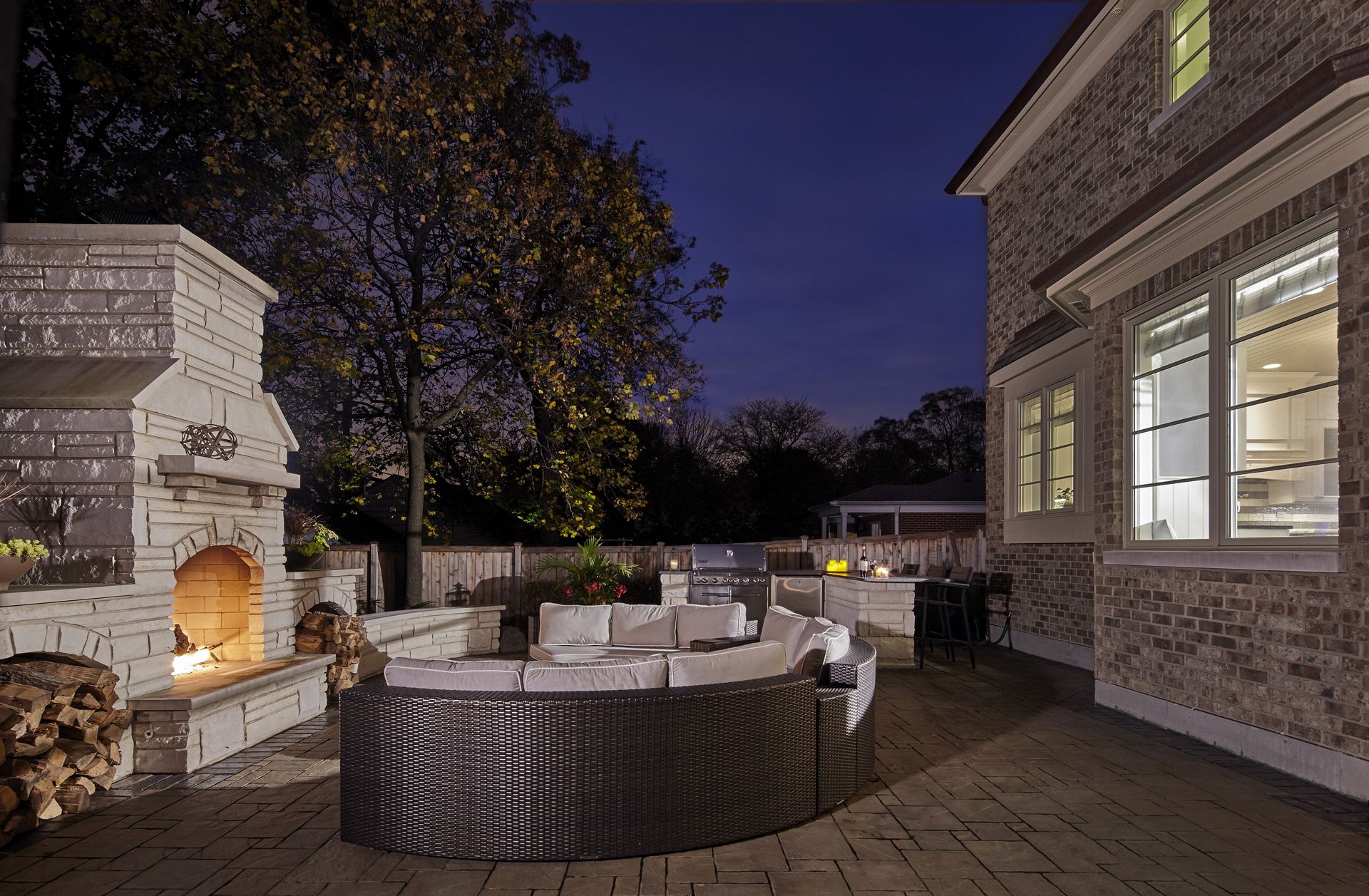 A patio with a fireplace and a couch at night