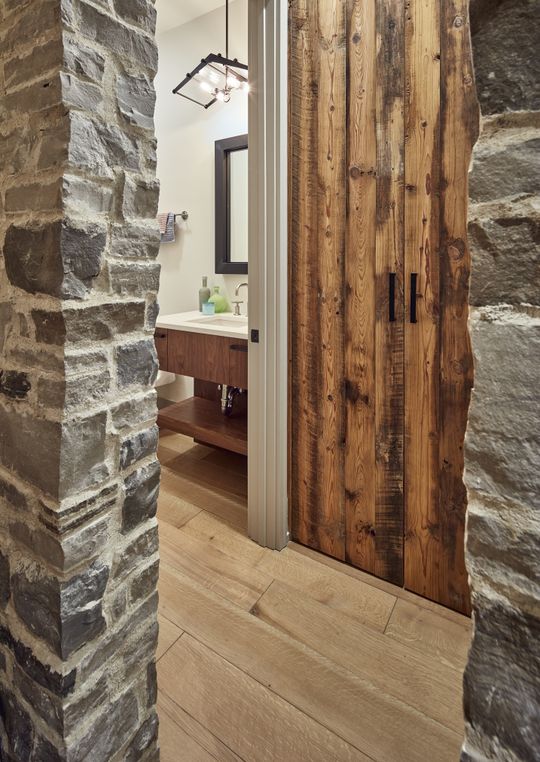 A bathroom with a wooden door and a stone wall.