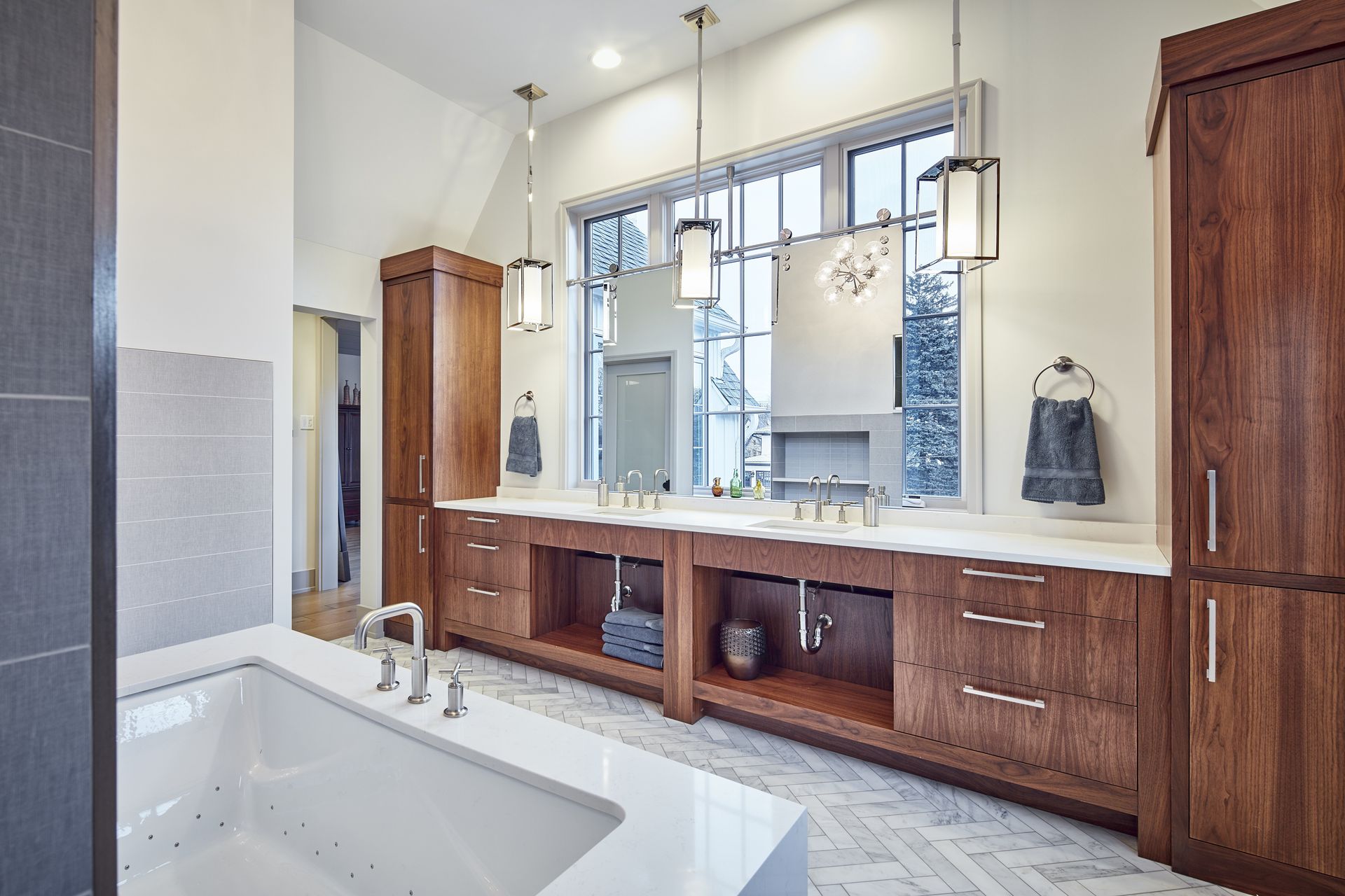 A bathroom with two sinks , a tub , and a large window.