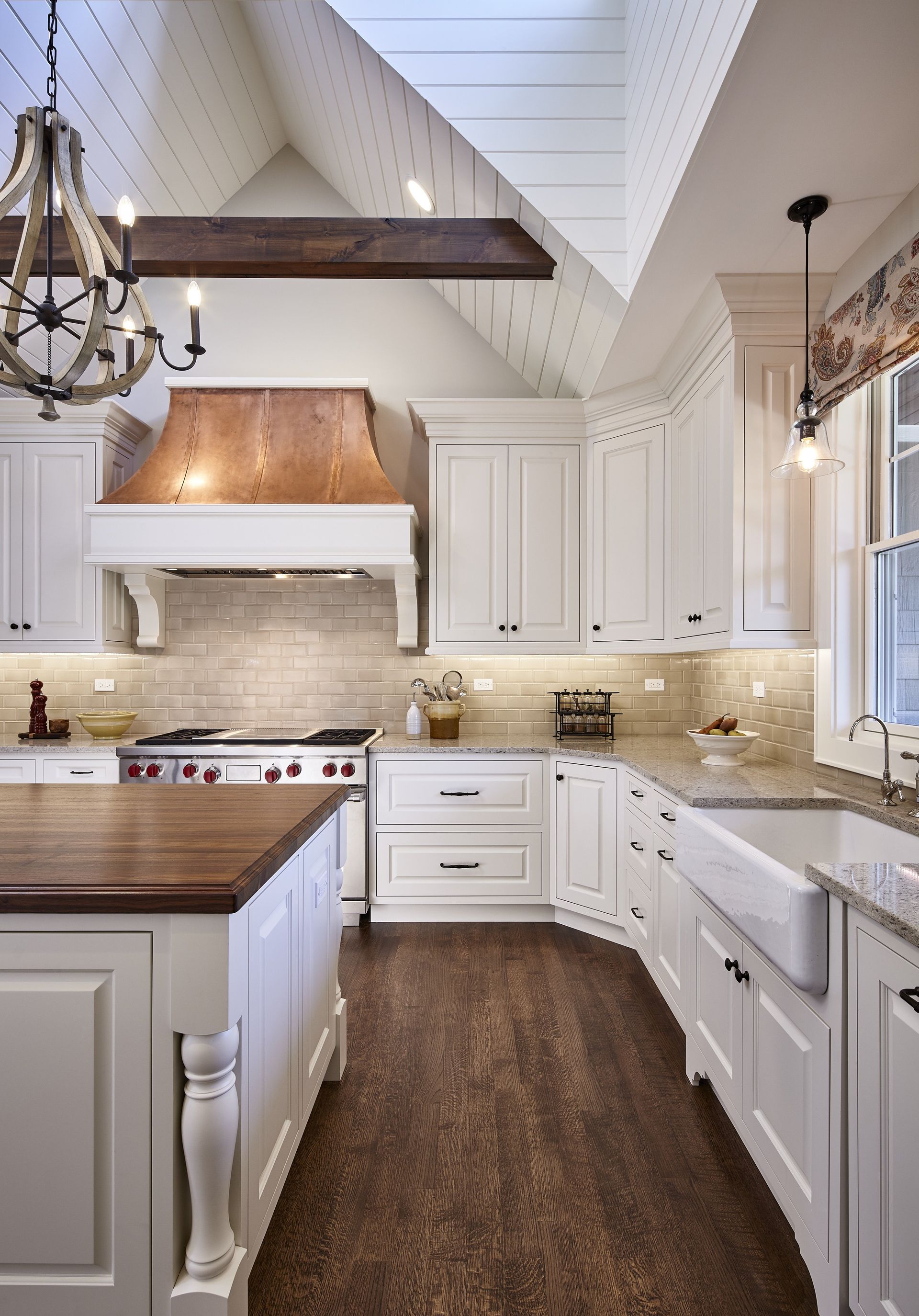 A kitchen with white cabinets and a copper hood