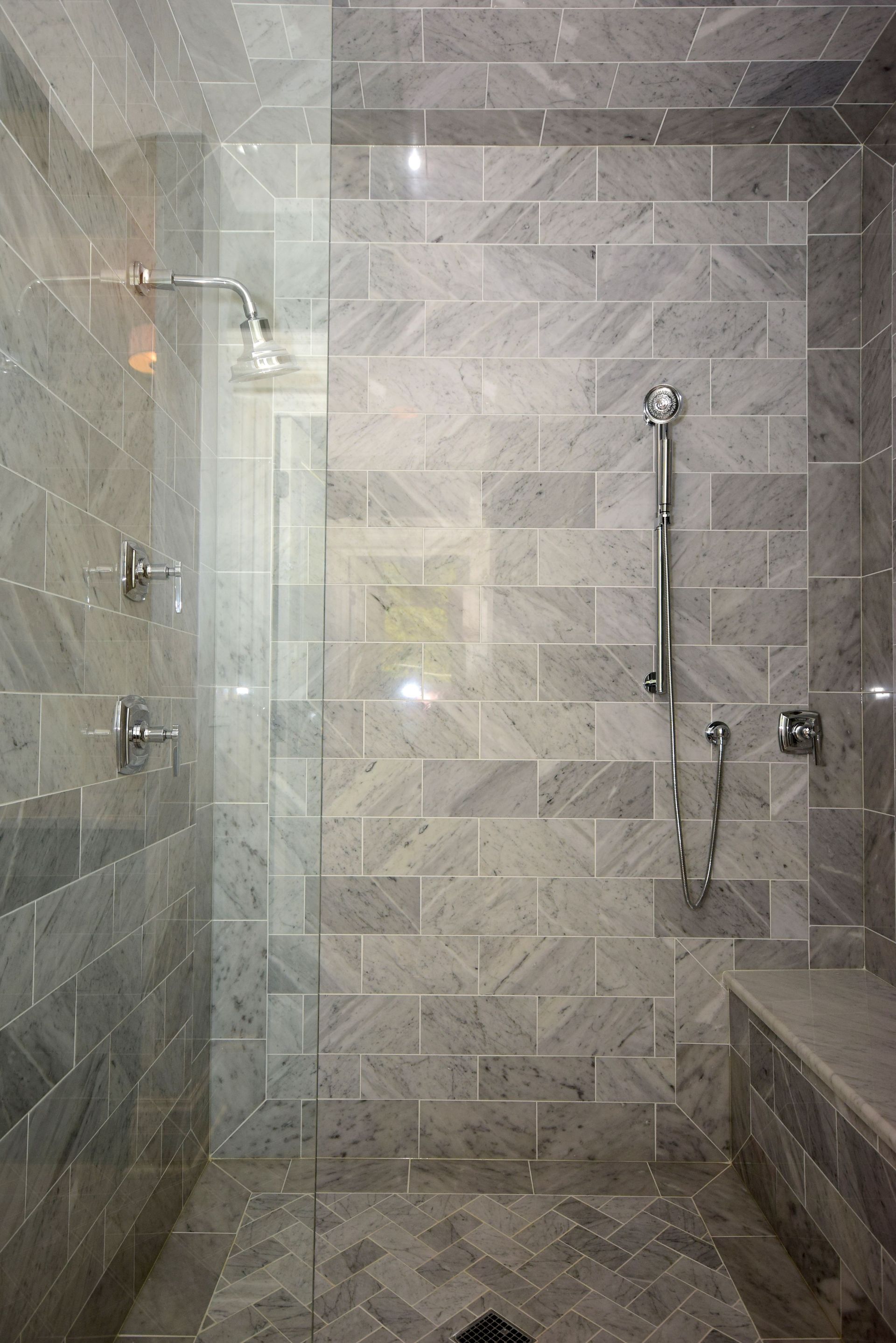A bathroom with a walk in shower and a bench.