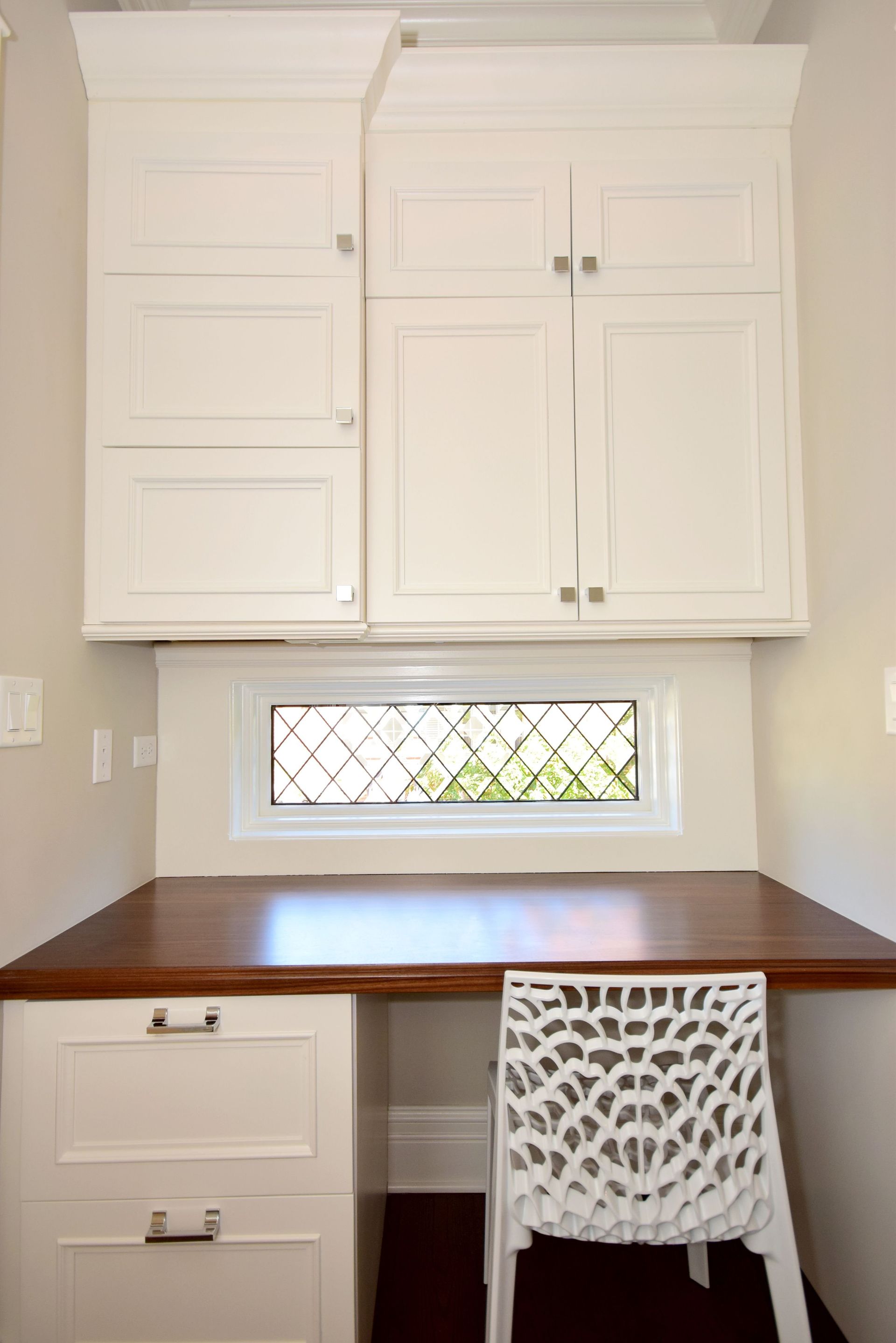 A desk with a chair underneath it and a window above it