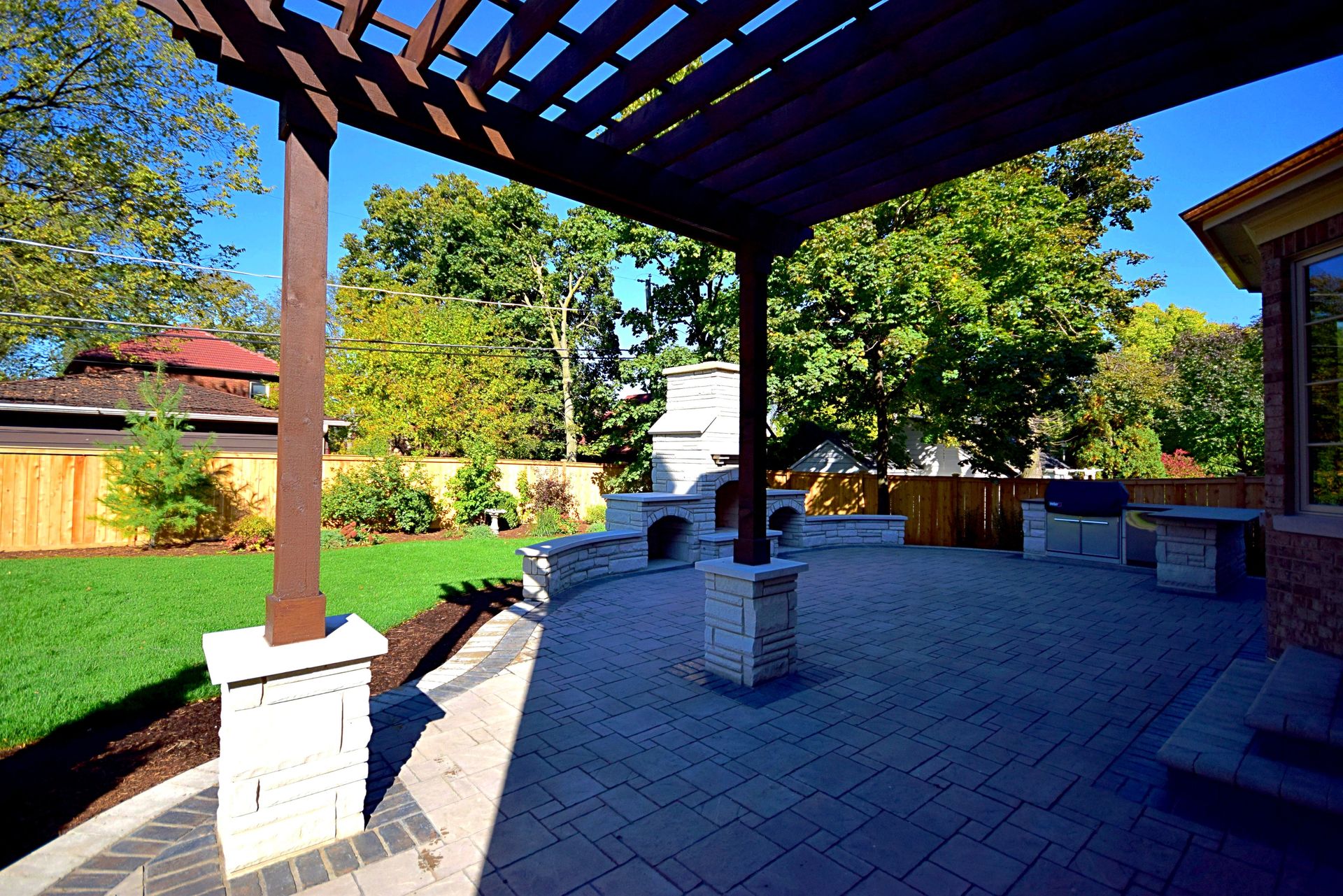 A patio with a pergola and a brick walkway