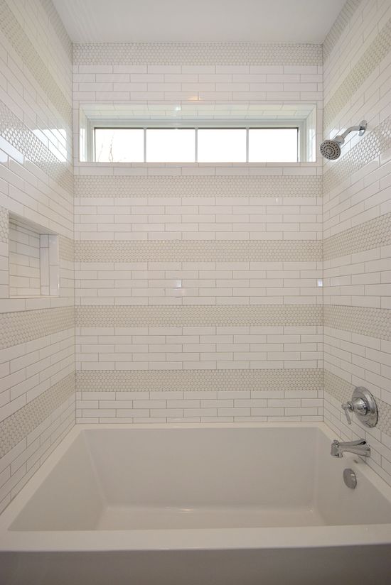 A bathroom with a tub , shower , and window.