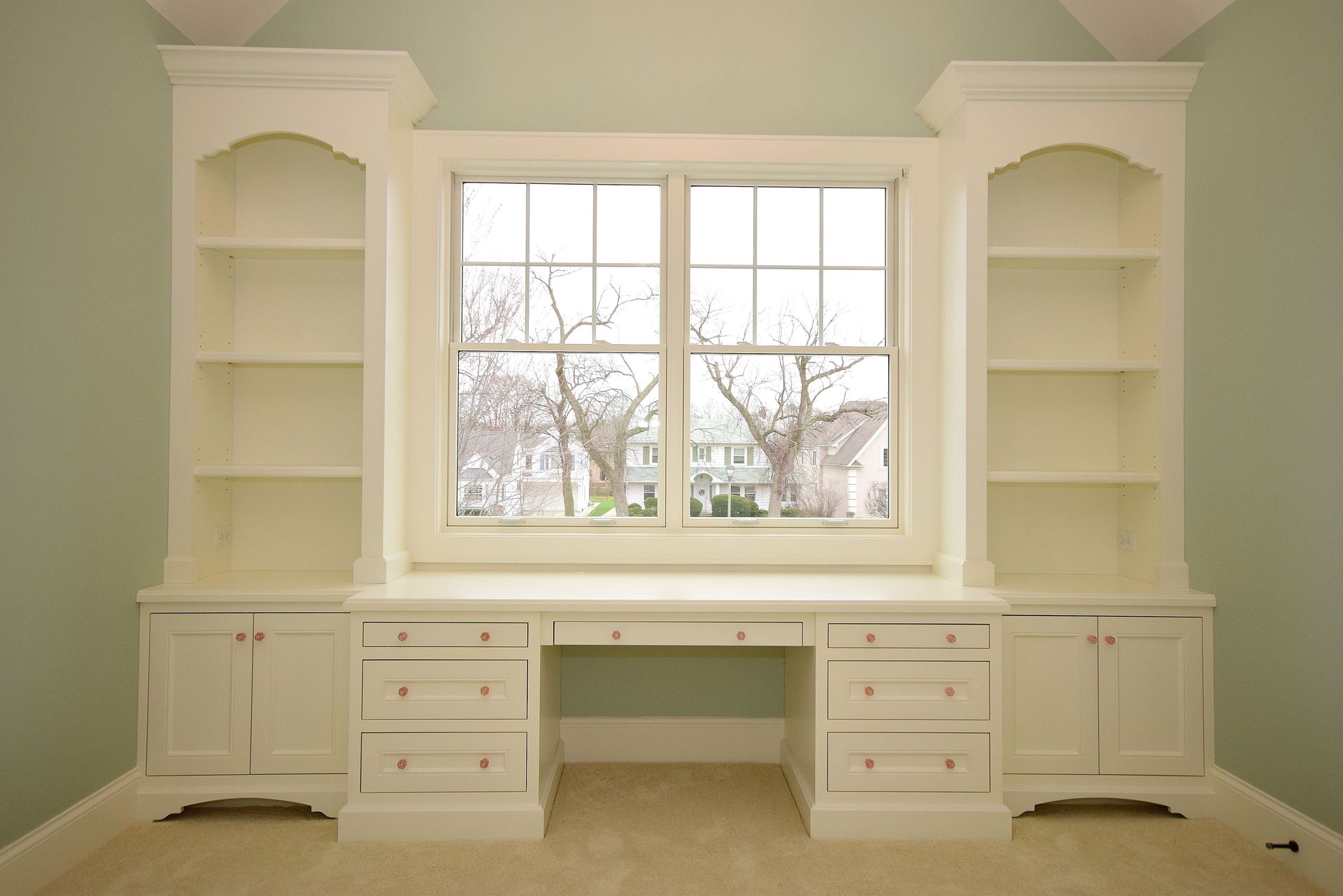 A room with a desk and shelves and a window