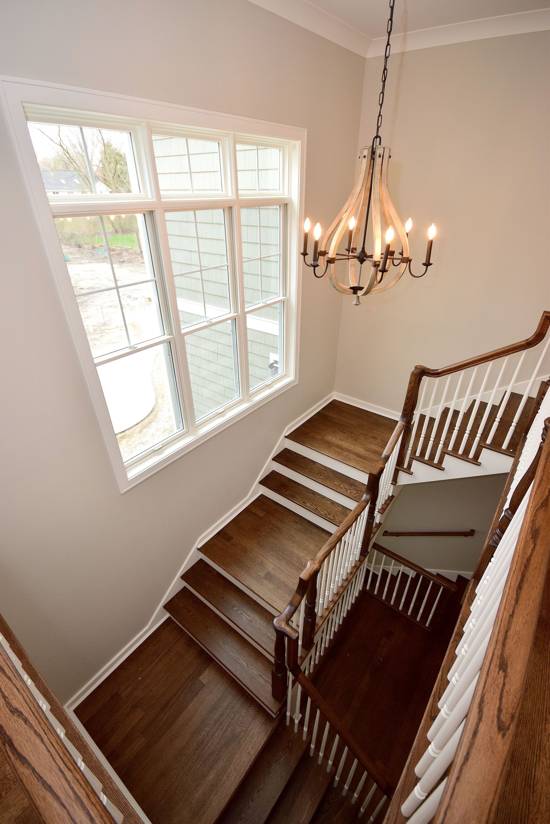 A wooden staircase with a white railing and a chandelier hanging from the ceiling.