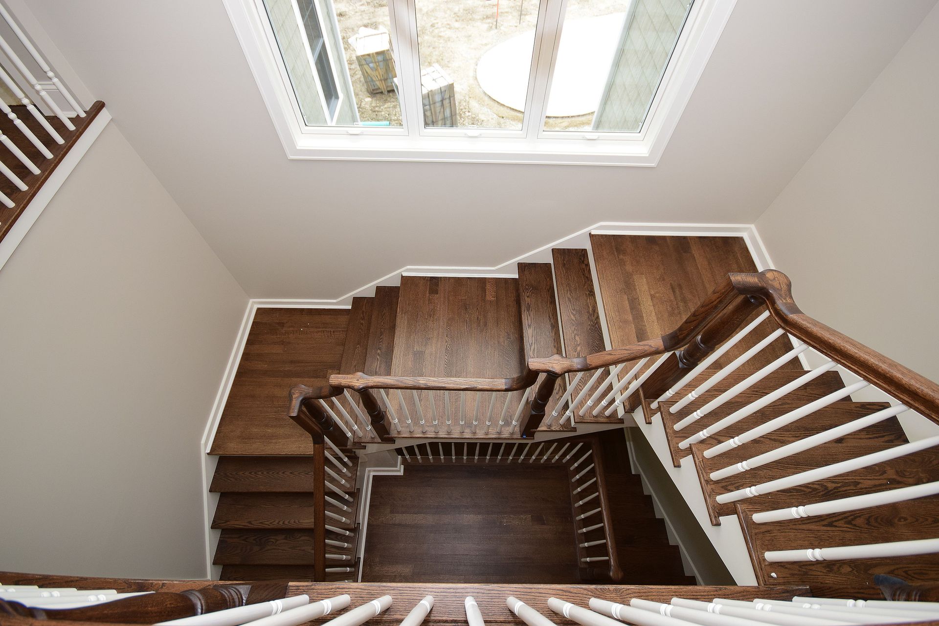 An aerial view of a wooden staircase with white railings and a window.