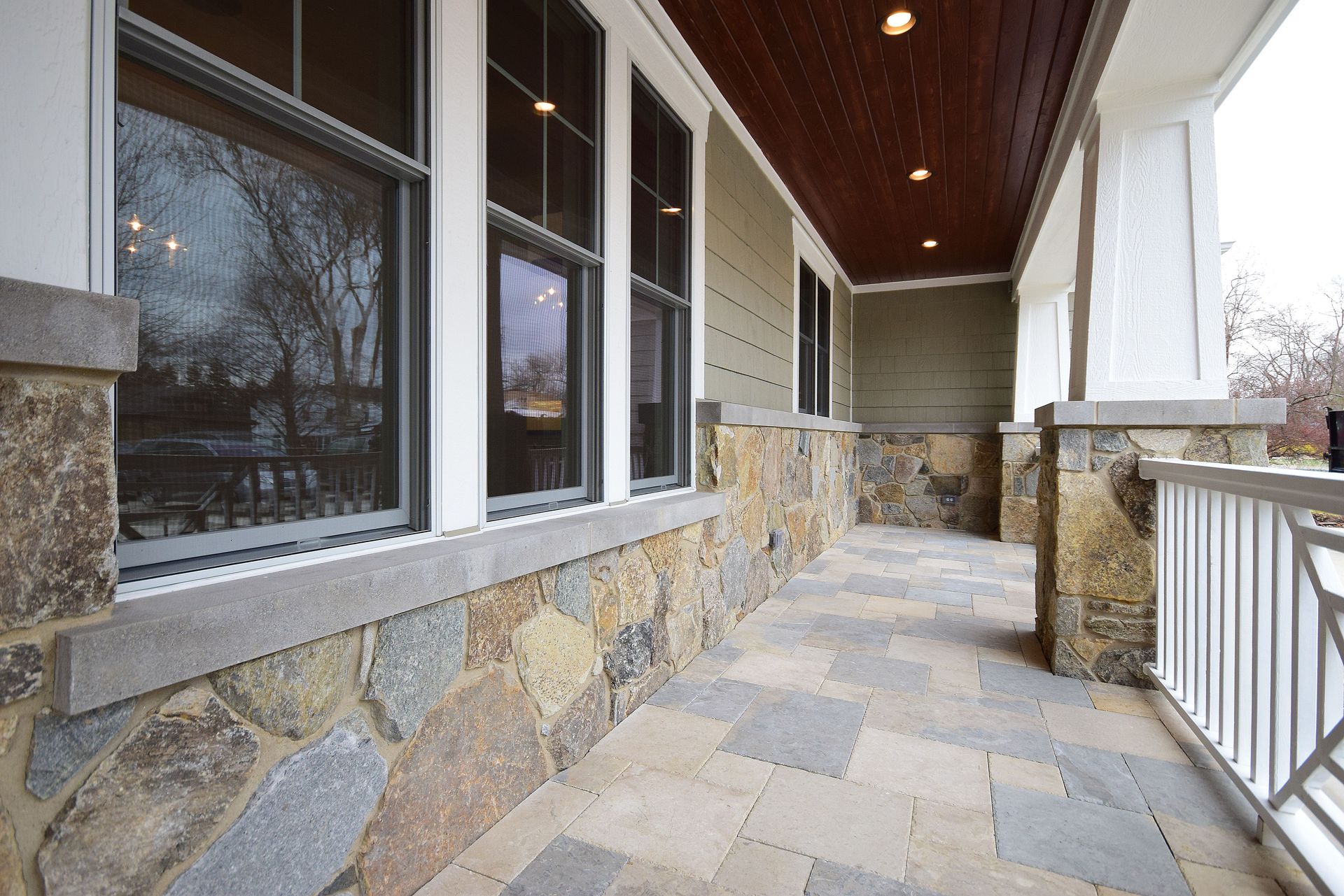 A porch with a stone wall and lots of windows