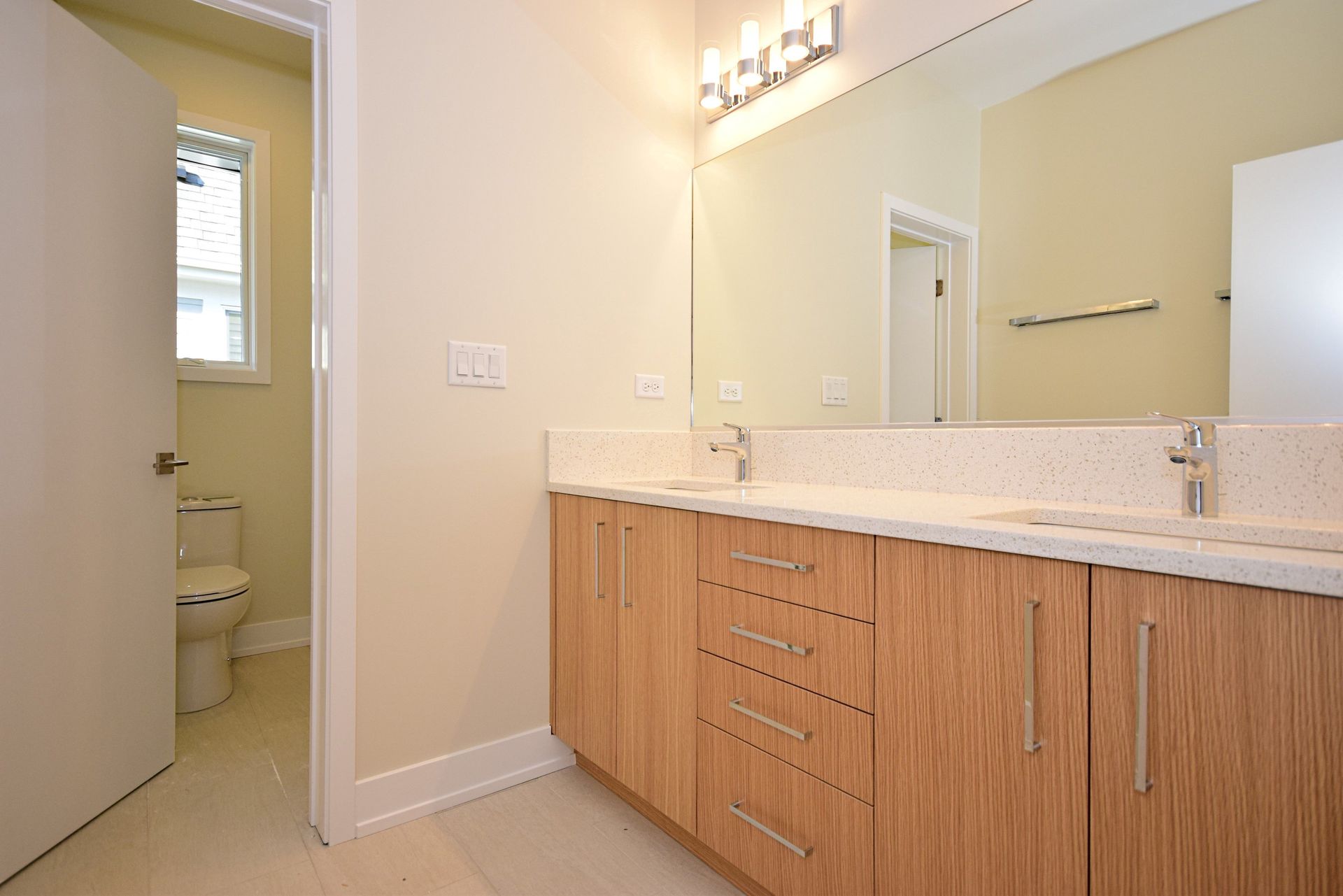 A bathroom with two sinks , a toilet and a mirror.