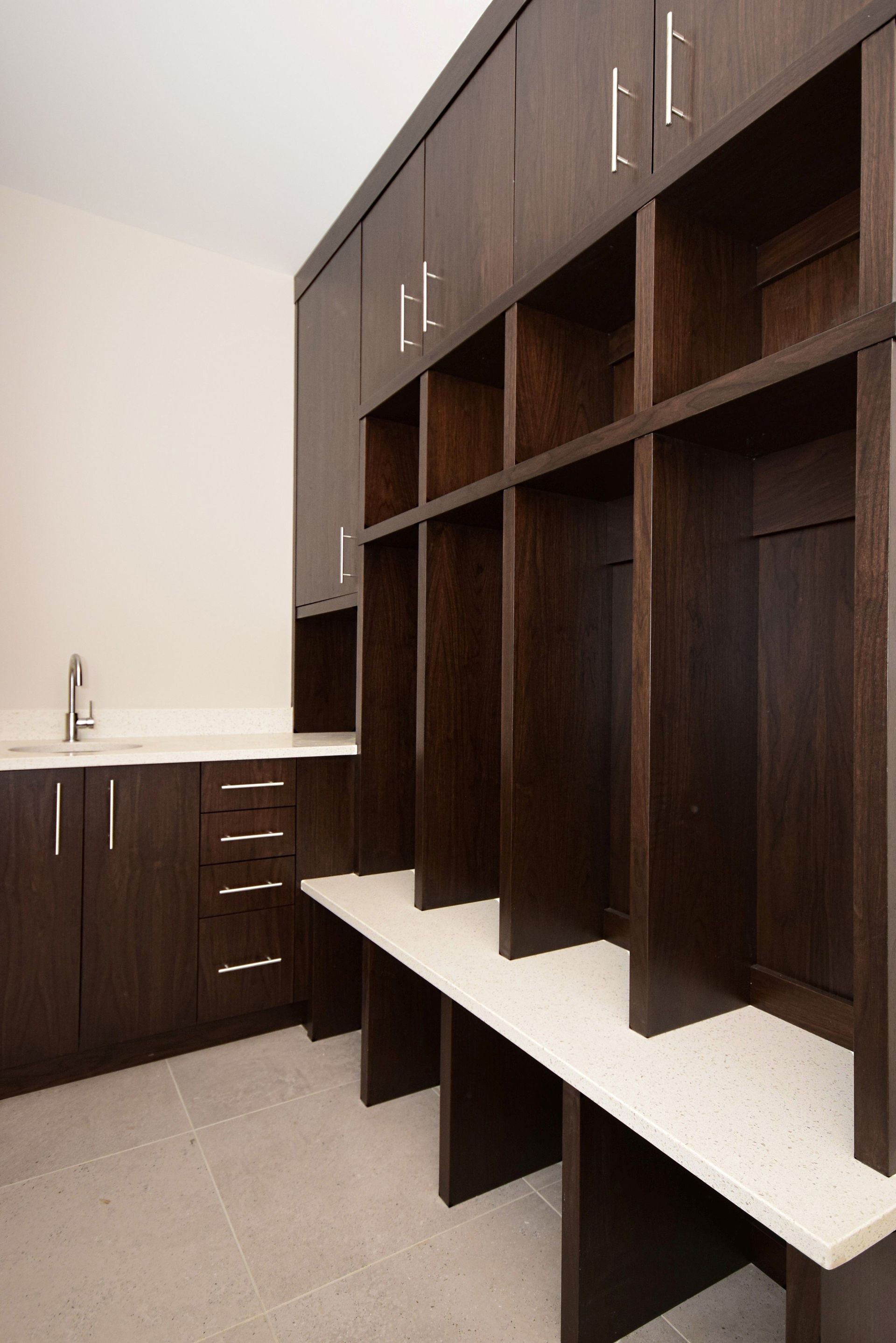 A locker room with lots of shelves and a sink.