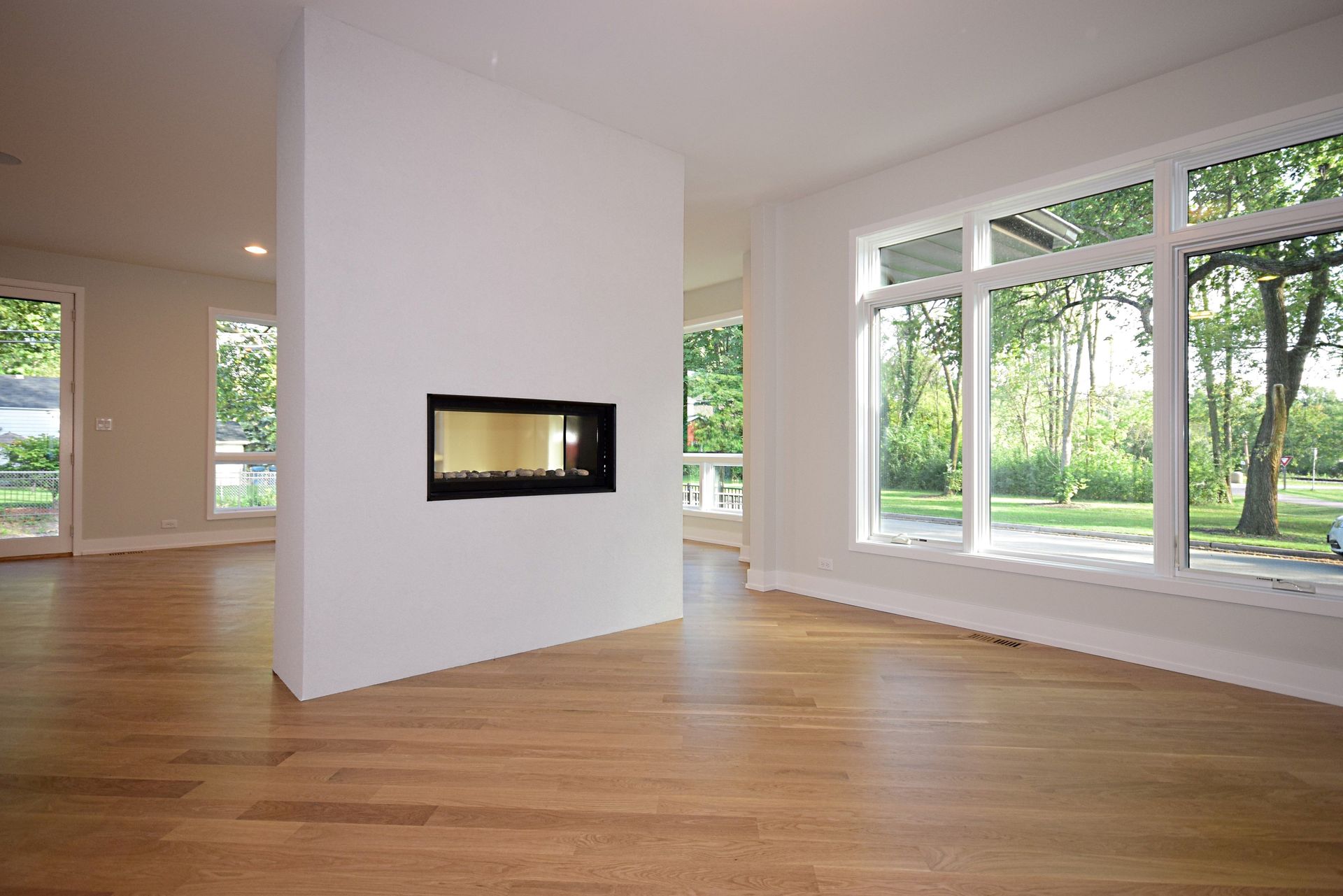 An empty living room with a fireplace and lots of windows