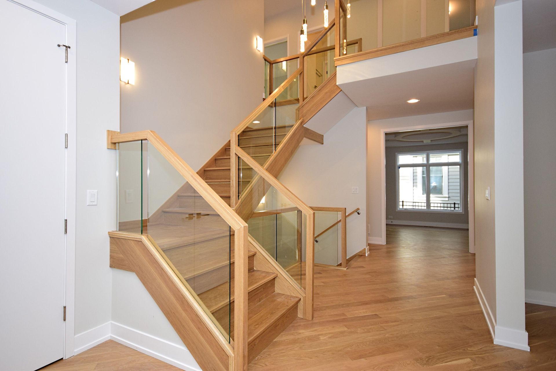 A wooden staircase with a glass railing in a hallway