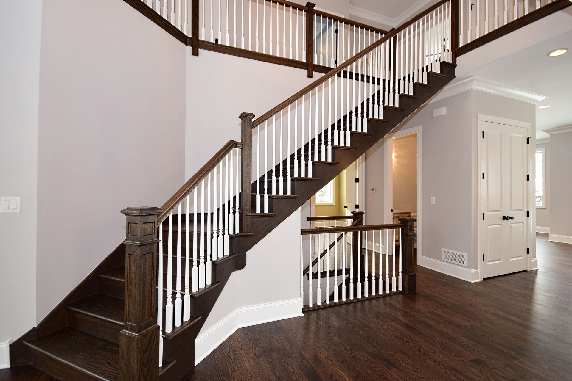 A wooden staircase with white railings in an empty house