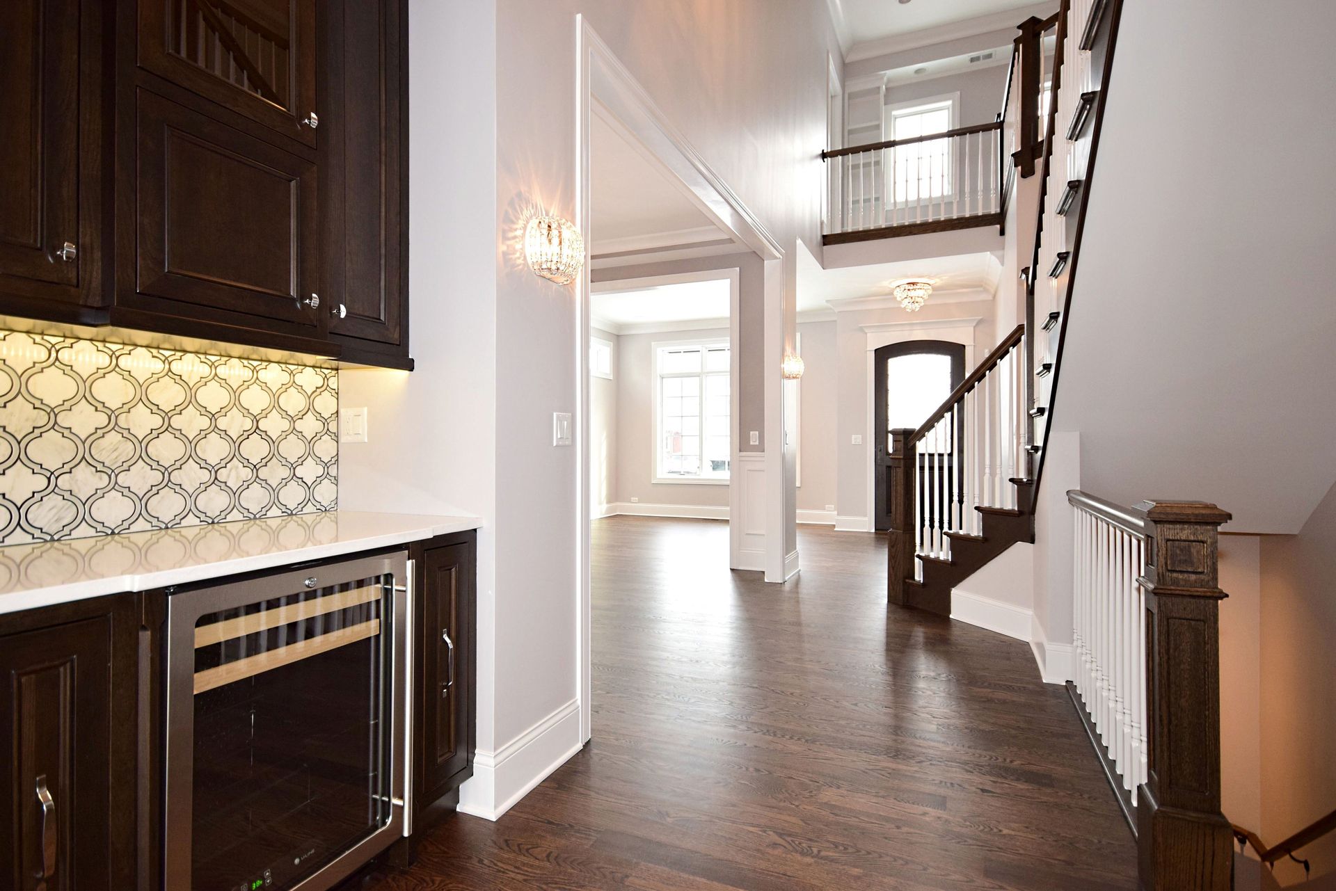 A hallway in a house with a staircase and a refrigerator