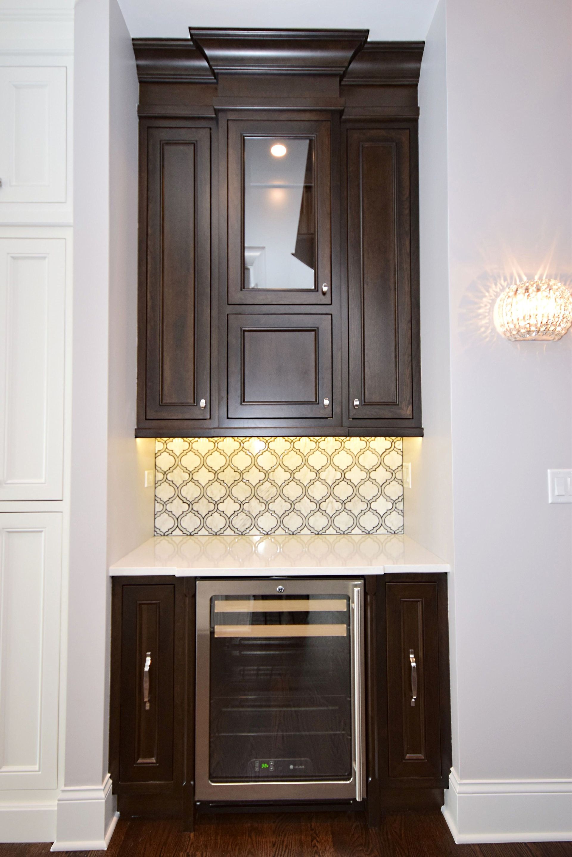 A kitchen with wooden cabinets and a stainless steel wine cooler.