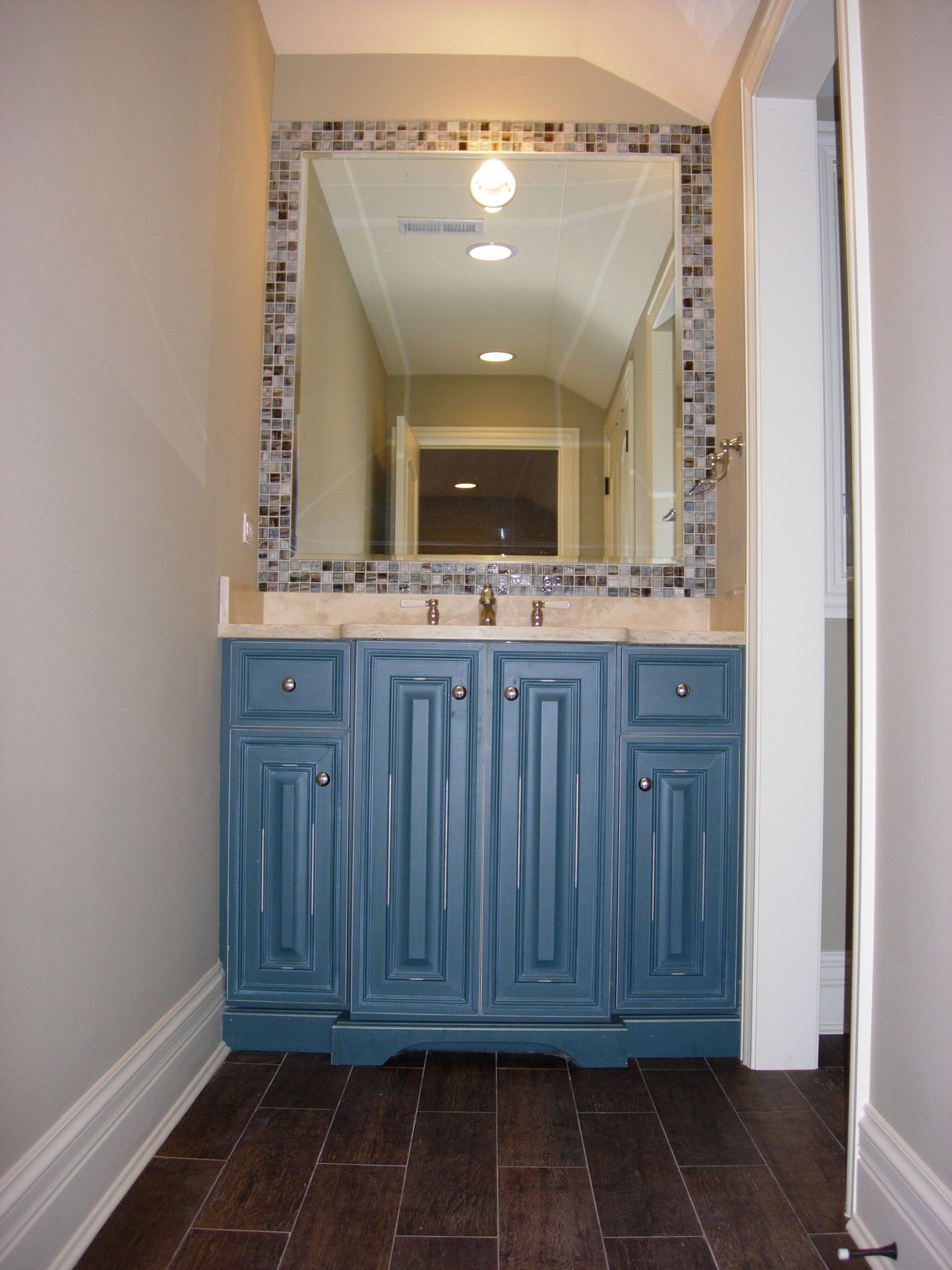 A bathroom with blue cabinets and a large mirror
