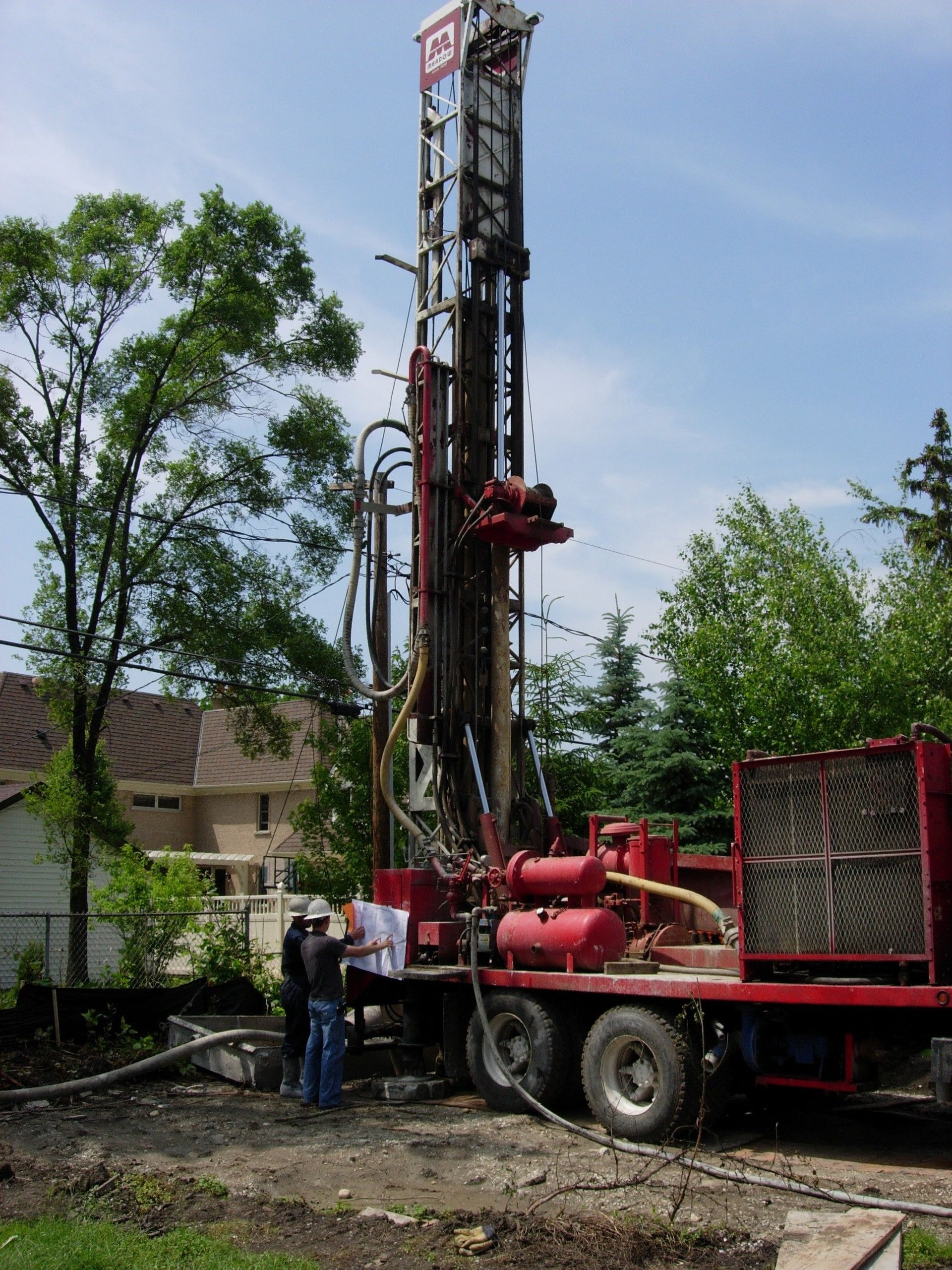 A red truck with a drilling rig on the back of it