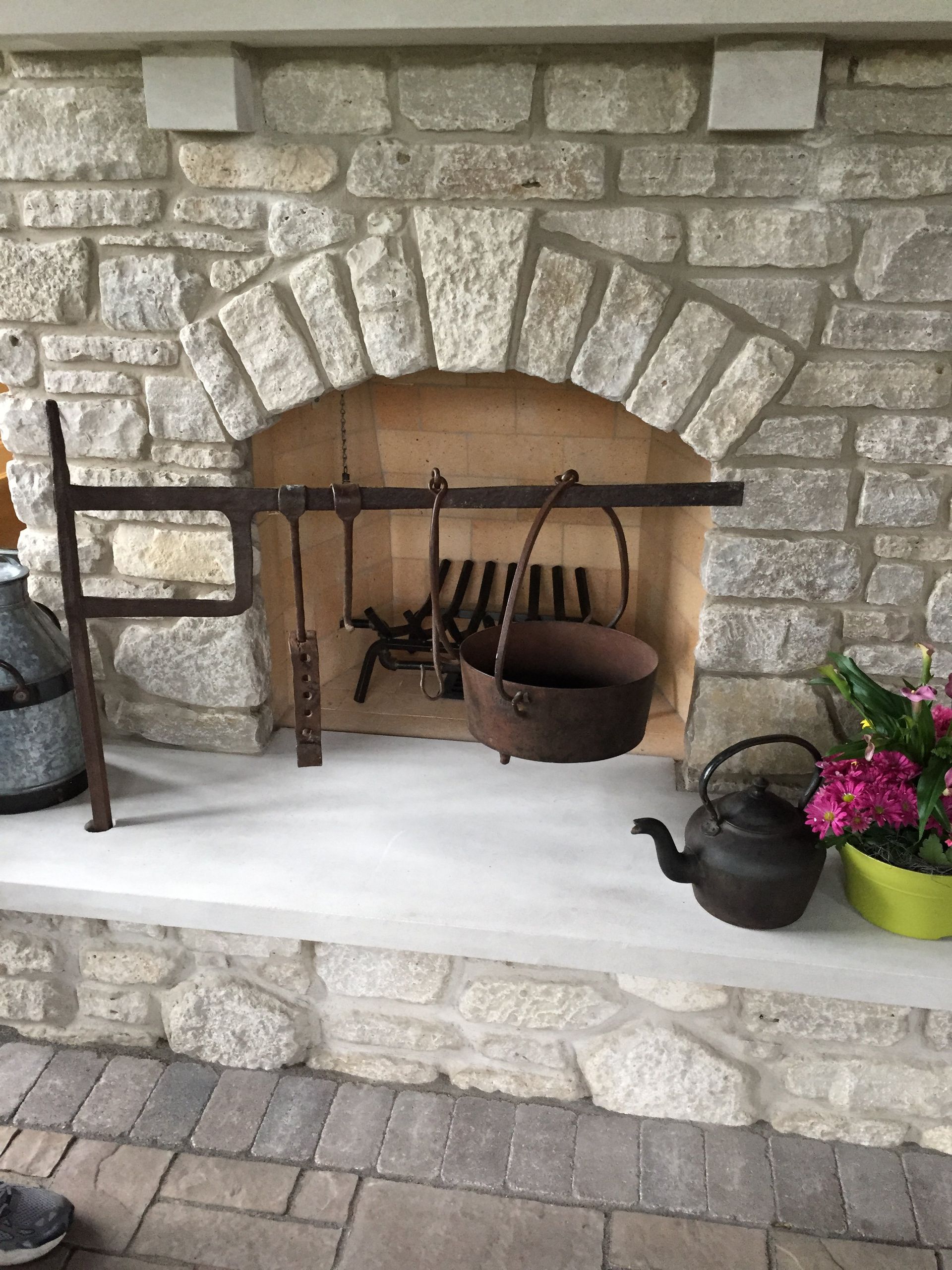 A stone fireplace with pots and pans hanging from it