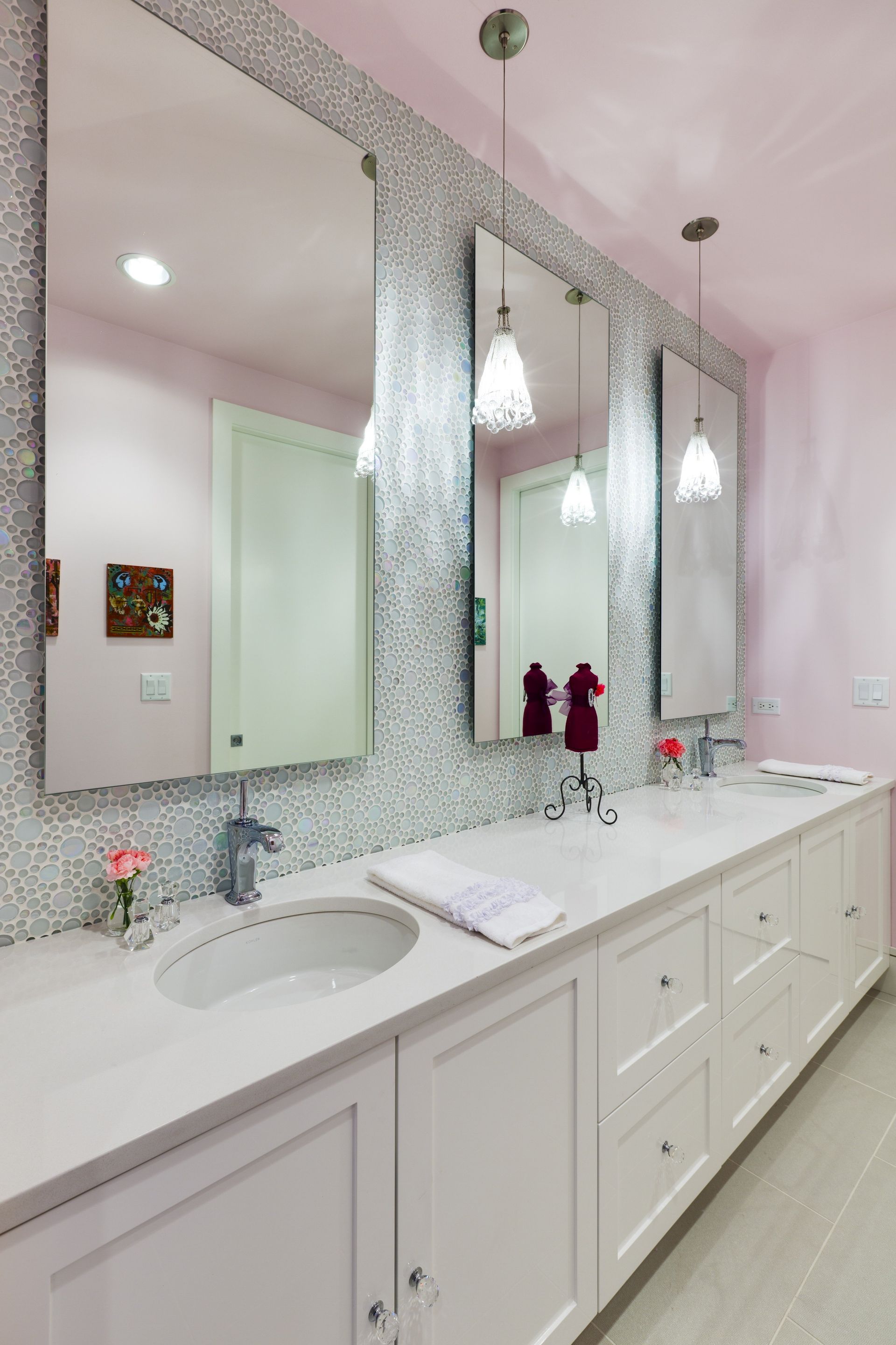 A bathroom with two sinks , two mirrors and a pink ceiling.