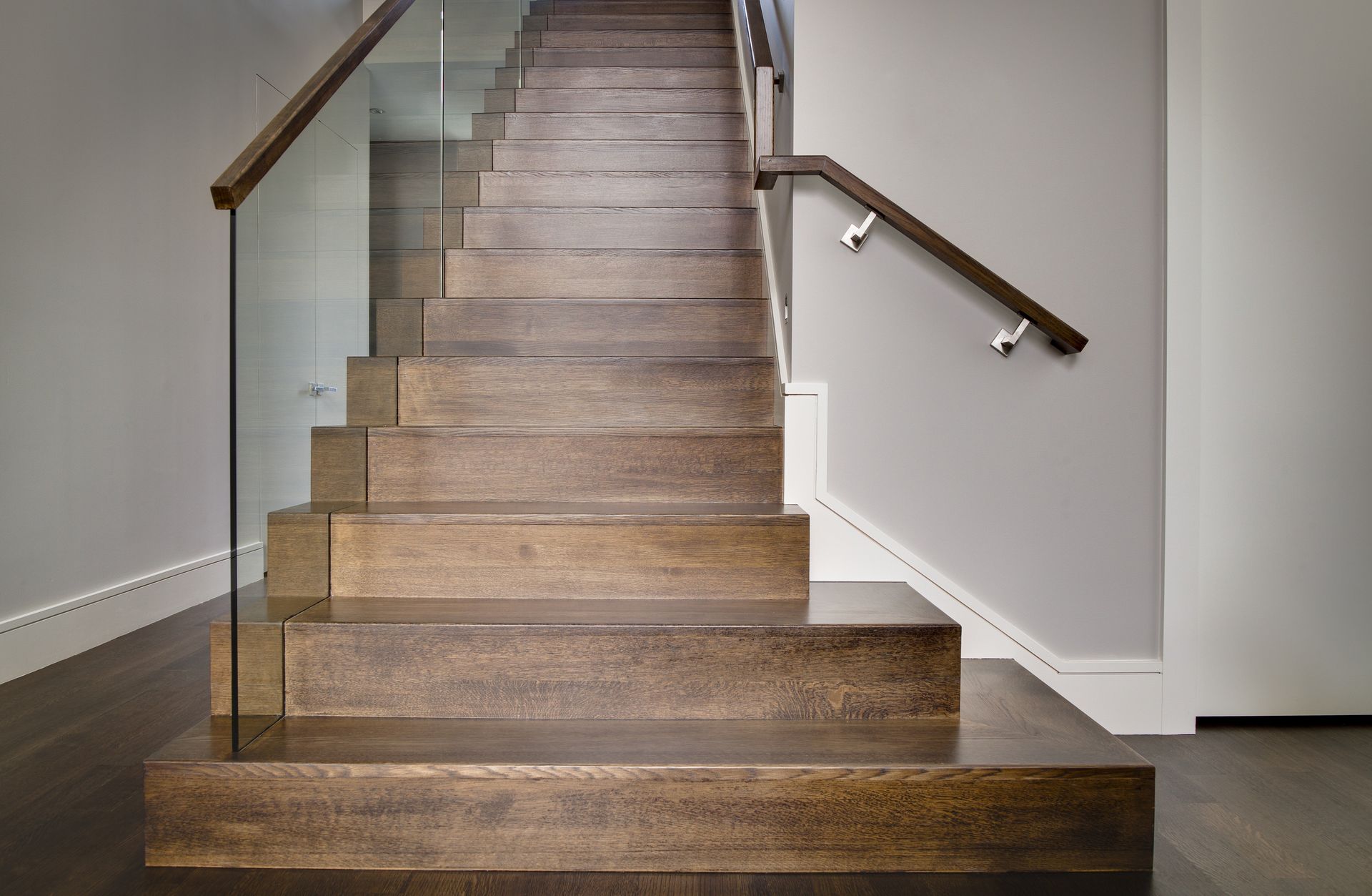 A wooden staircase with a glass railing in a house
