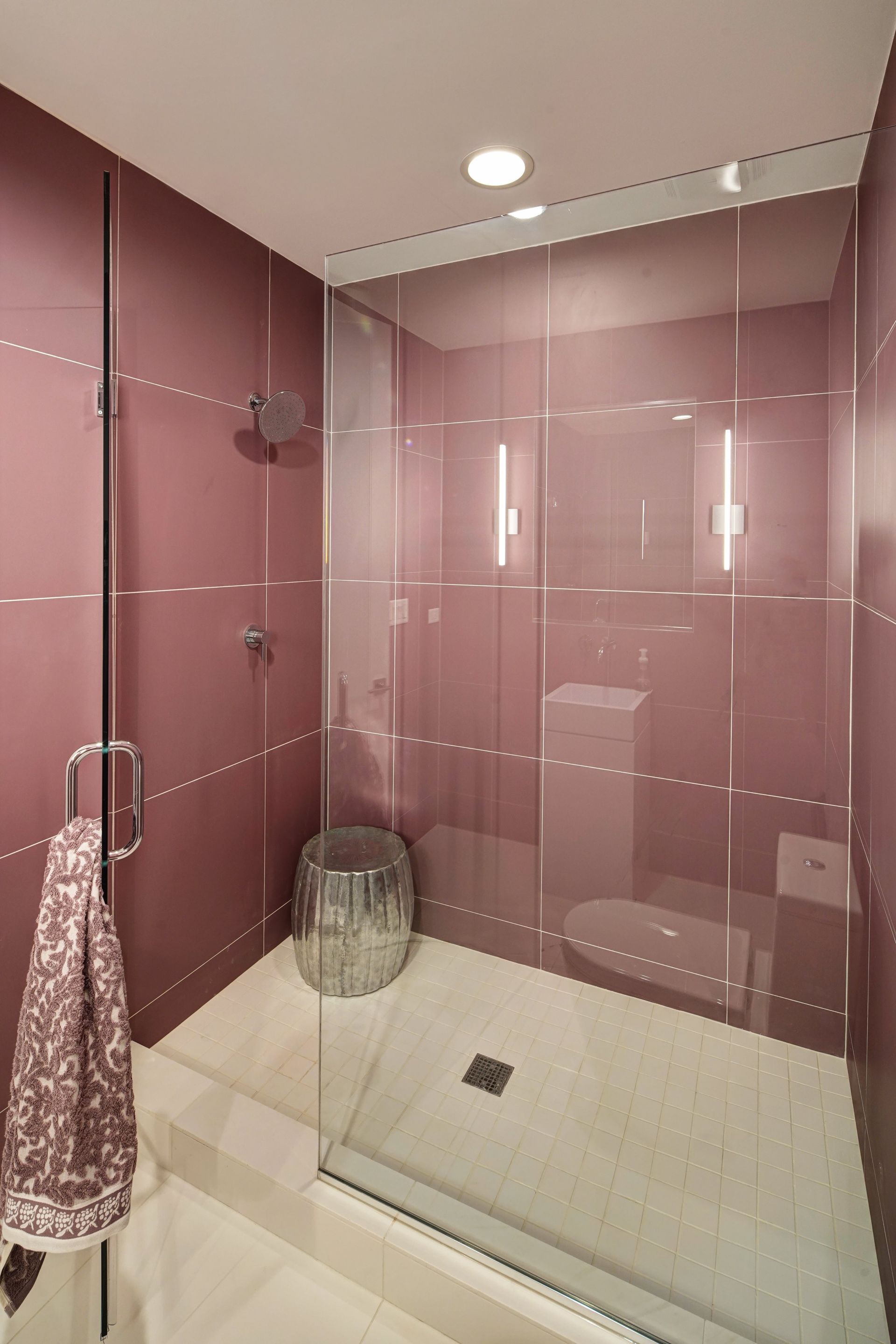 A bathroom with pink tiles and a walk in shower
