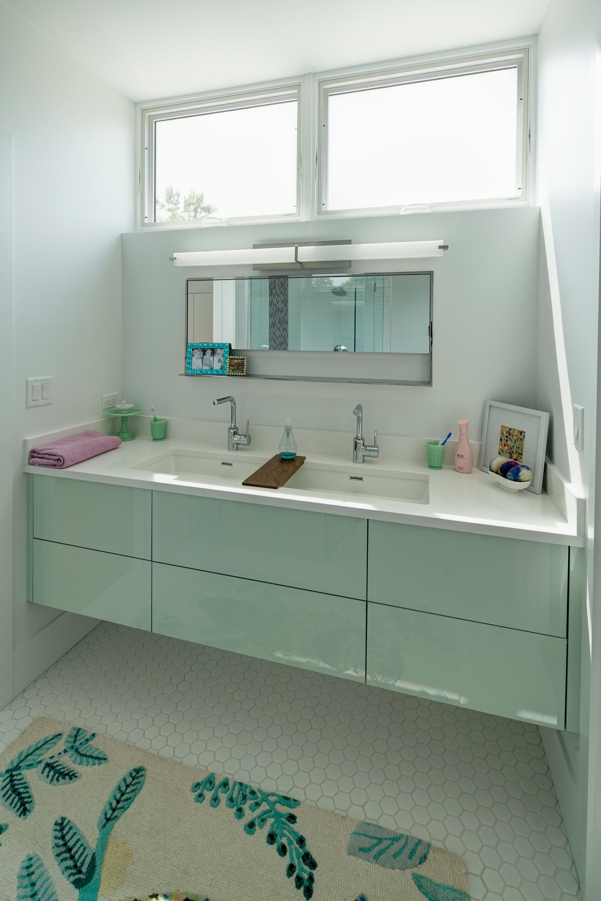 A bathroom with two sinks , a mirror and a rug.