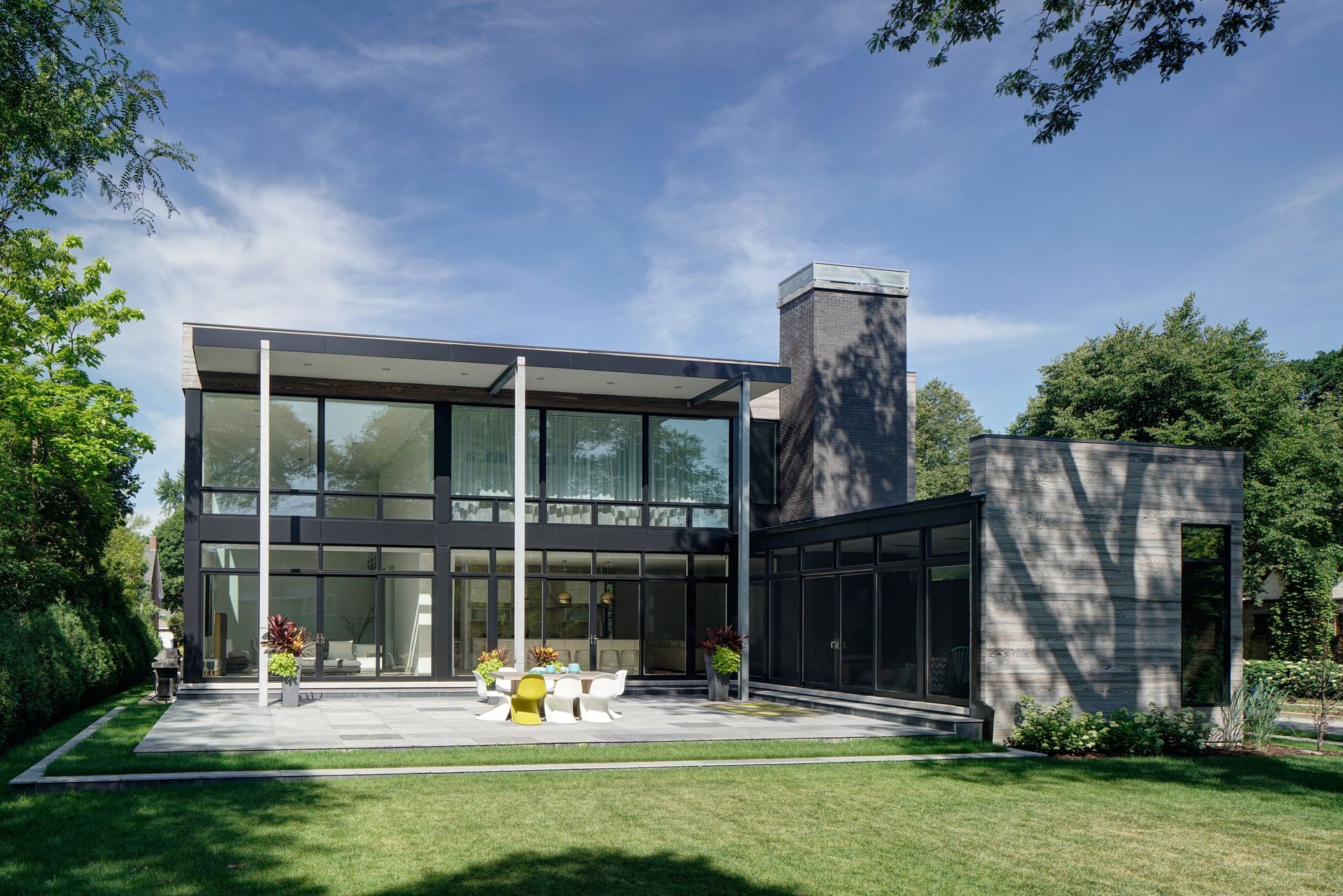 A large house with a lot of windows is surrounded by trees and grass.