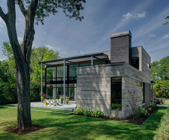 A modern house with a lot of windows and a tree in front of it