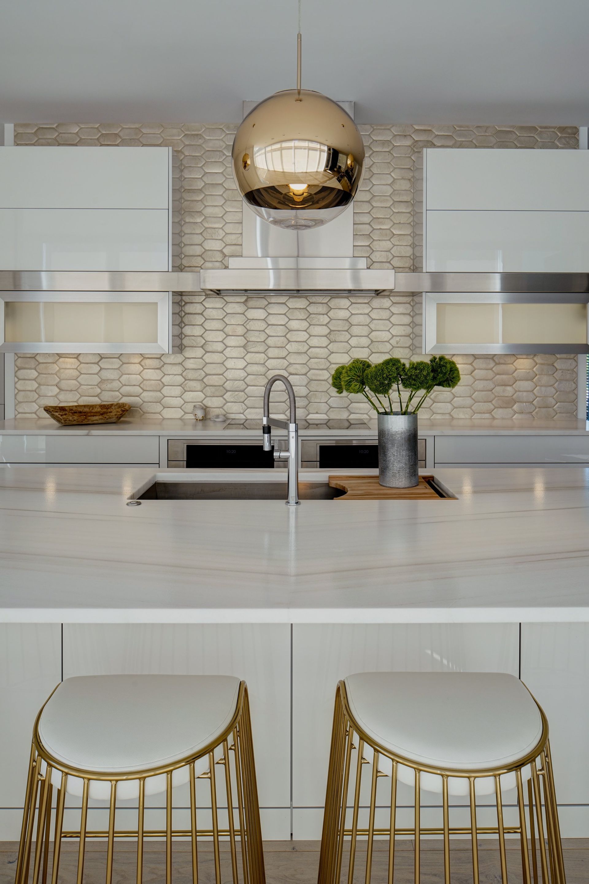 A kitchen with a sink , stools and a pendant light.