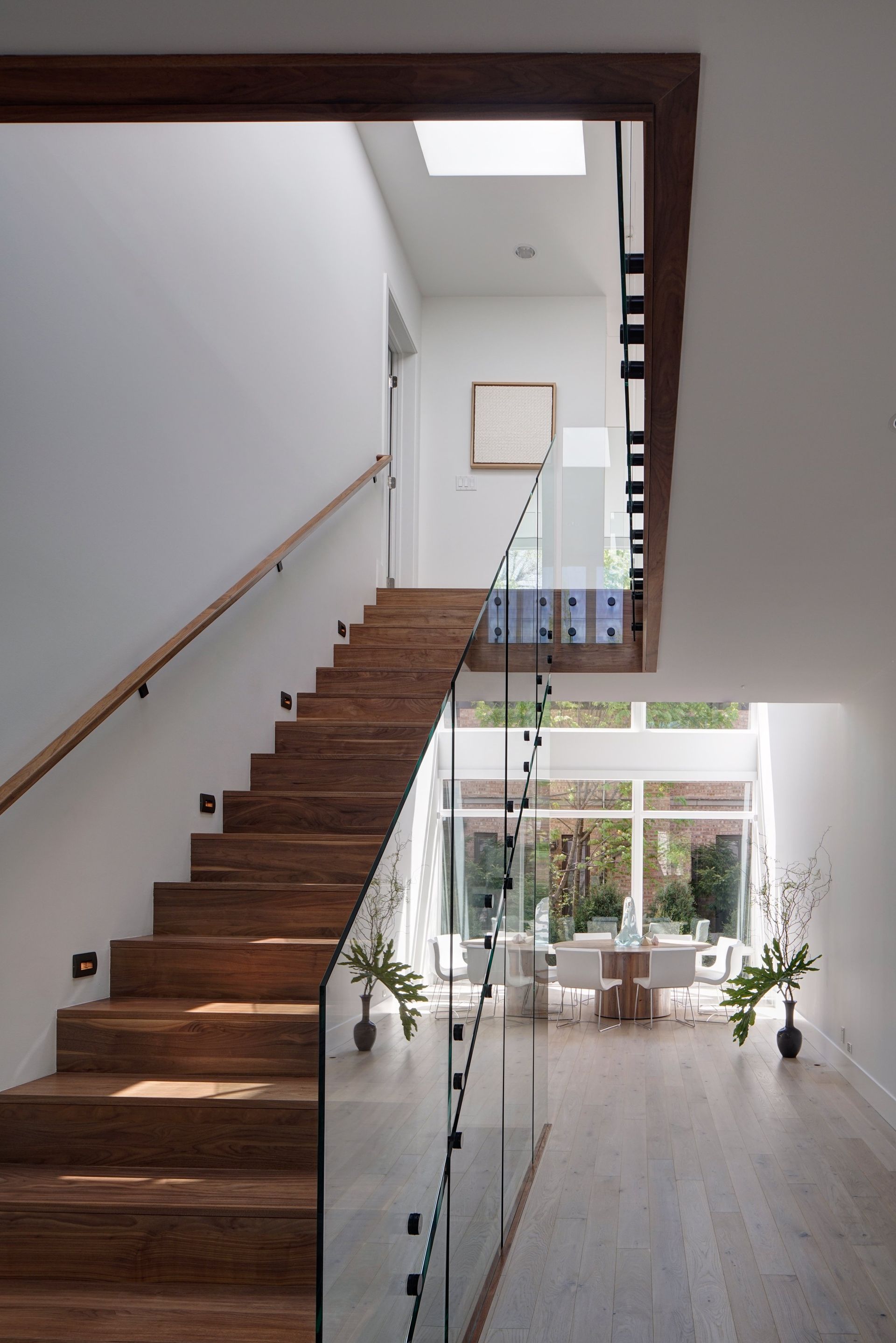 A wooden staircase with a glass railing leading up to the second floor
