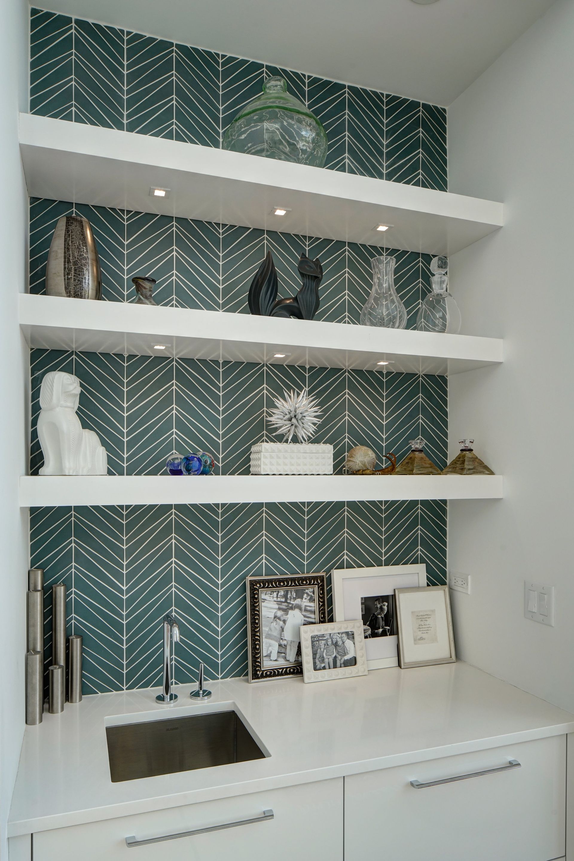 A kitchen with a sink and shelves with a chevron pattern on the wall.