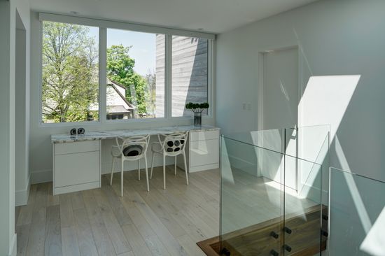 A room with a desk and chairs and a glass railing