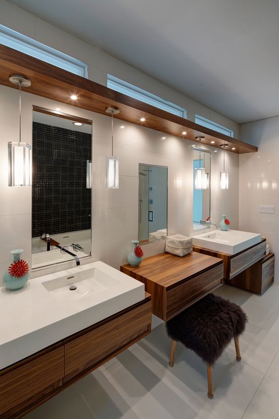 A bathroom with two sinks , two mirrors and a bench.