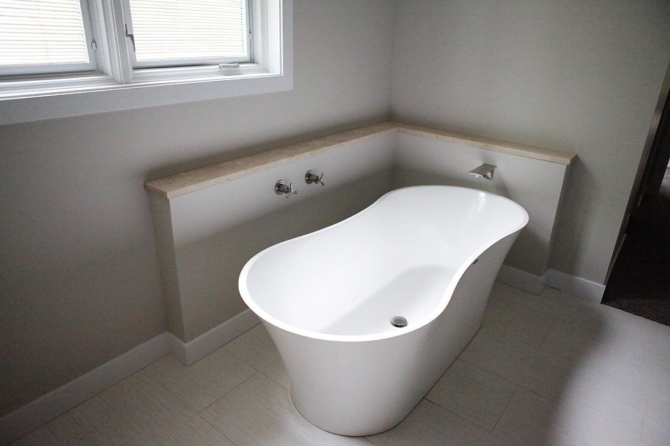 A white bathtub is sitting in a bathroom next to a window.